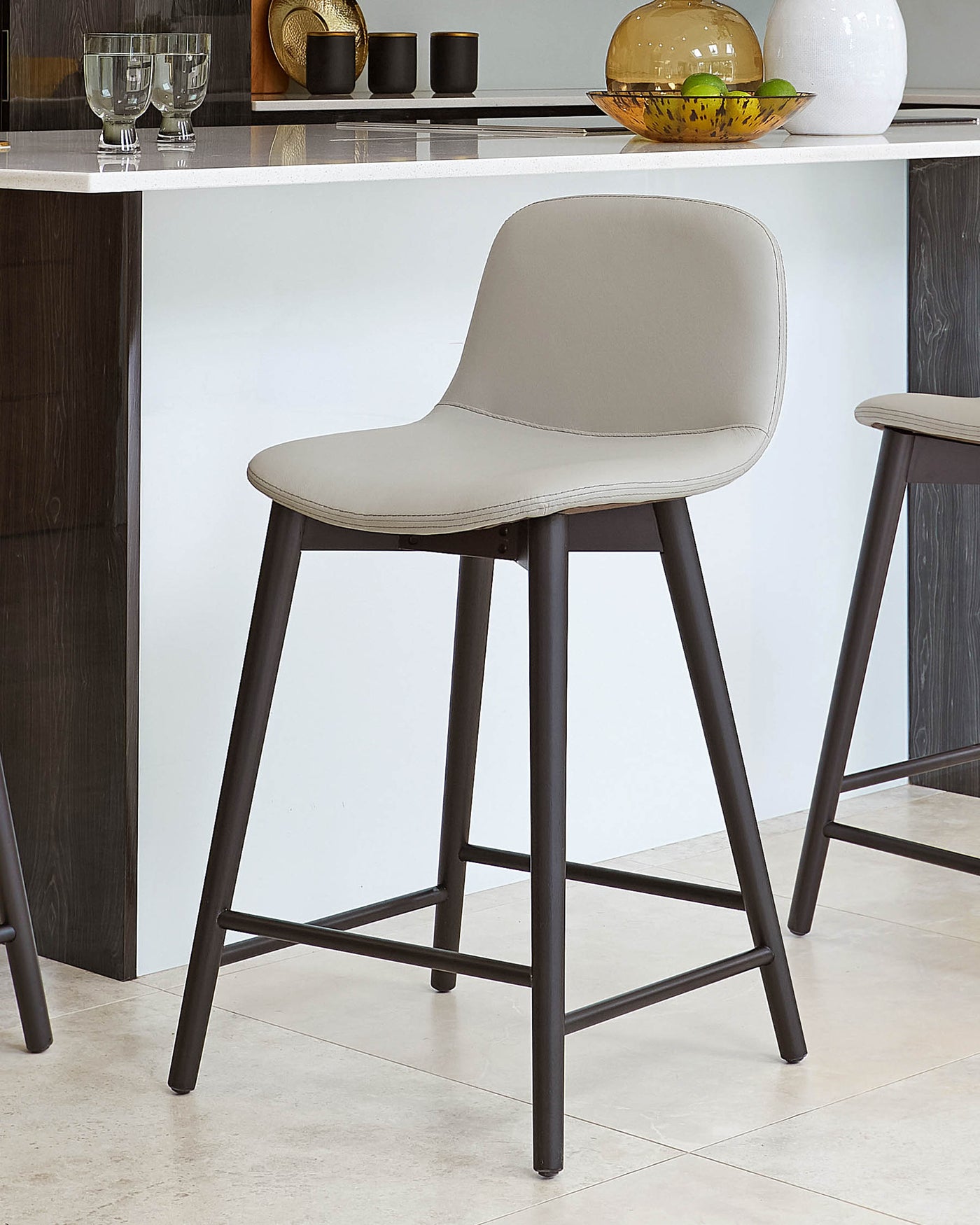 Modern bar stool with a light grey upholstered seat and backrest, mounted on a minimalist, angled, four-legged black metal frame.
