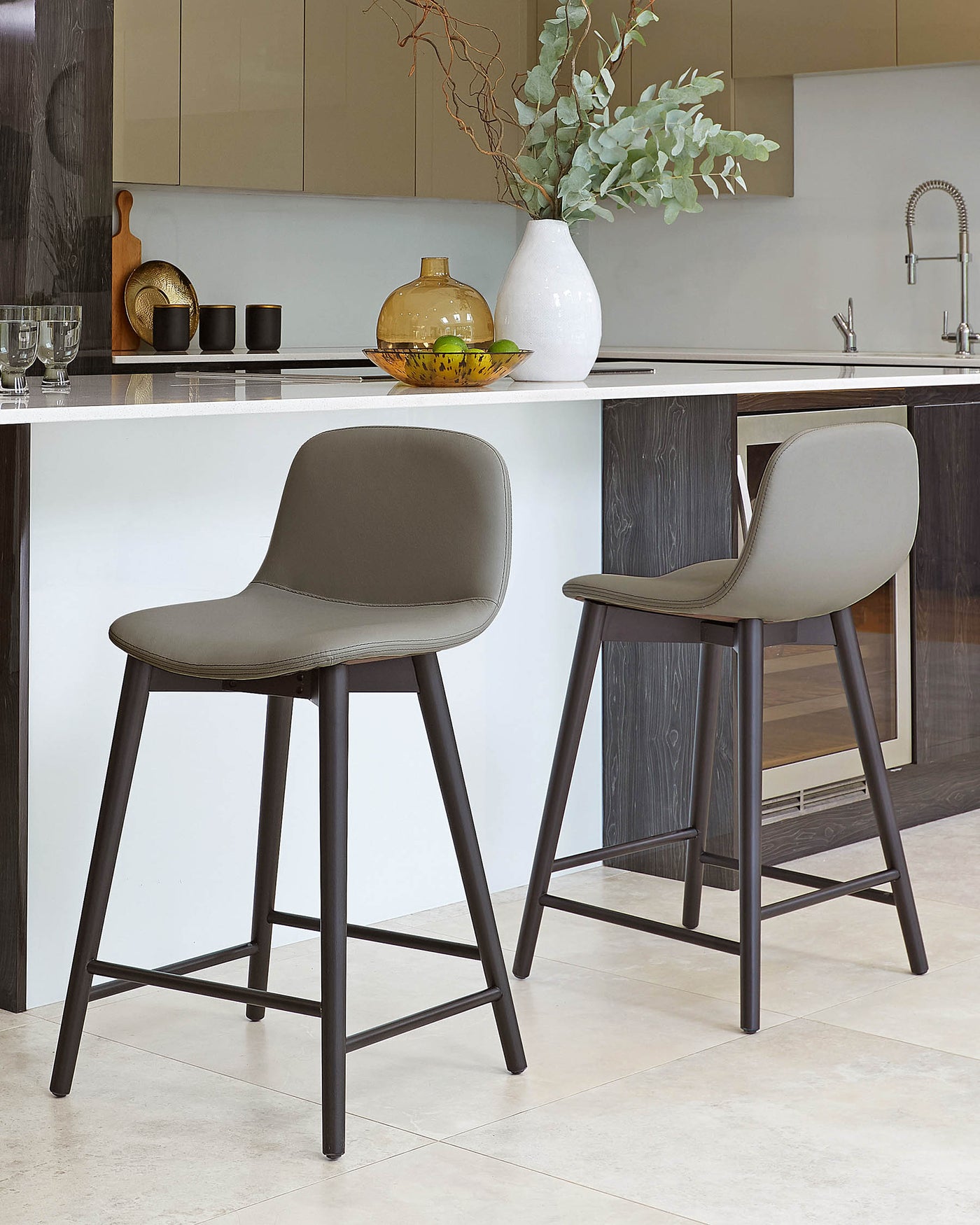 Modern minimalist bar stools with grey faux leather seating and black metal legs in a contemporary kitchen setting.
