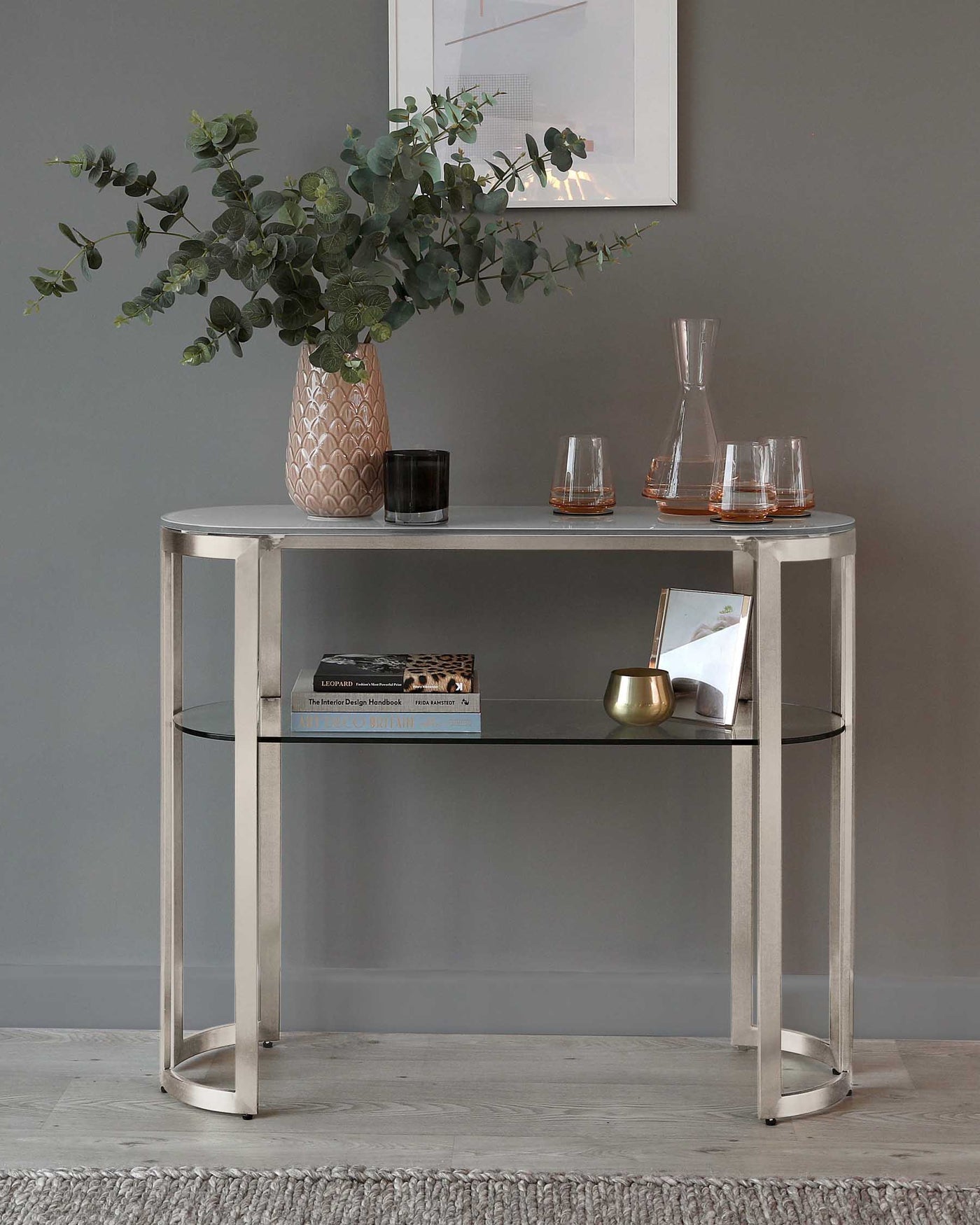 Elegant, modern half-moon console table with a polished metal frame and two-tiered glass shelves.