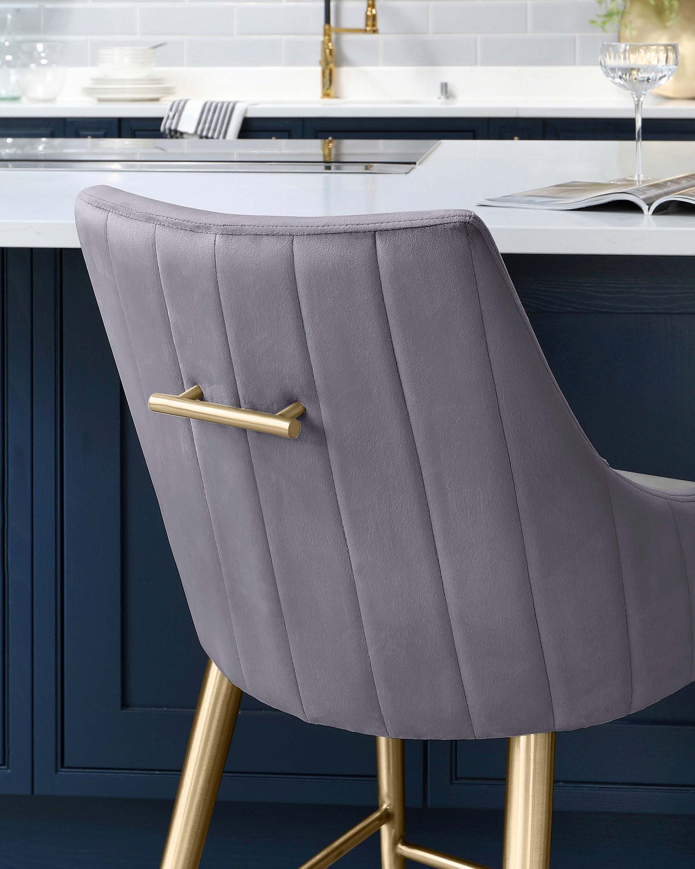 Elegant modern bar stool with a curved, channel-tufted backrest in a soft lavender shade, featuring sleek golden legs that taper to a point and a matching golden footrest.