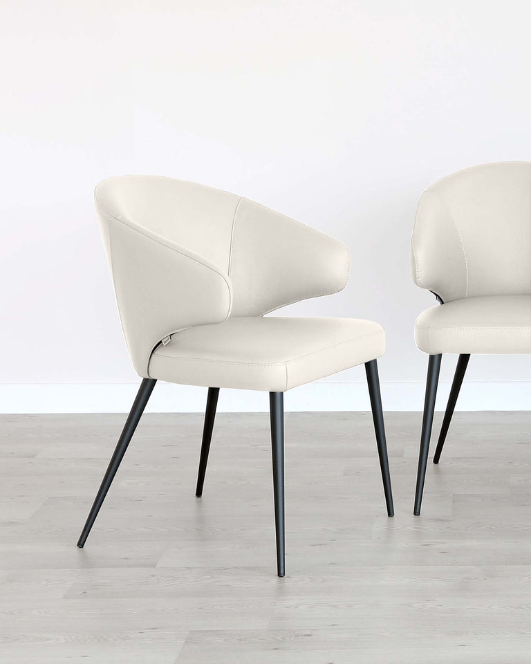 Two modern dining chairs with a sleek design, featuring cream upholstered seats and curved backrests. The chairs have slender, black metal legs, which provide a contemporary contrast to the light-coloured seat.