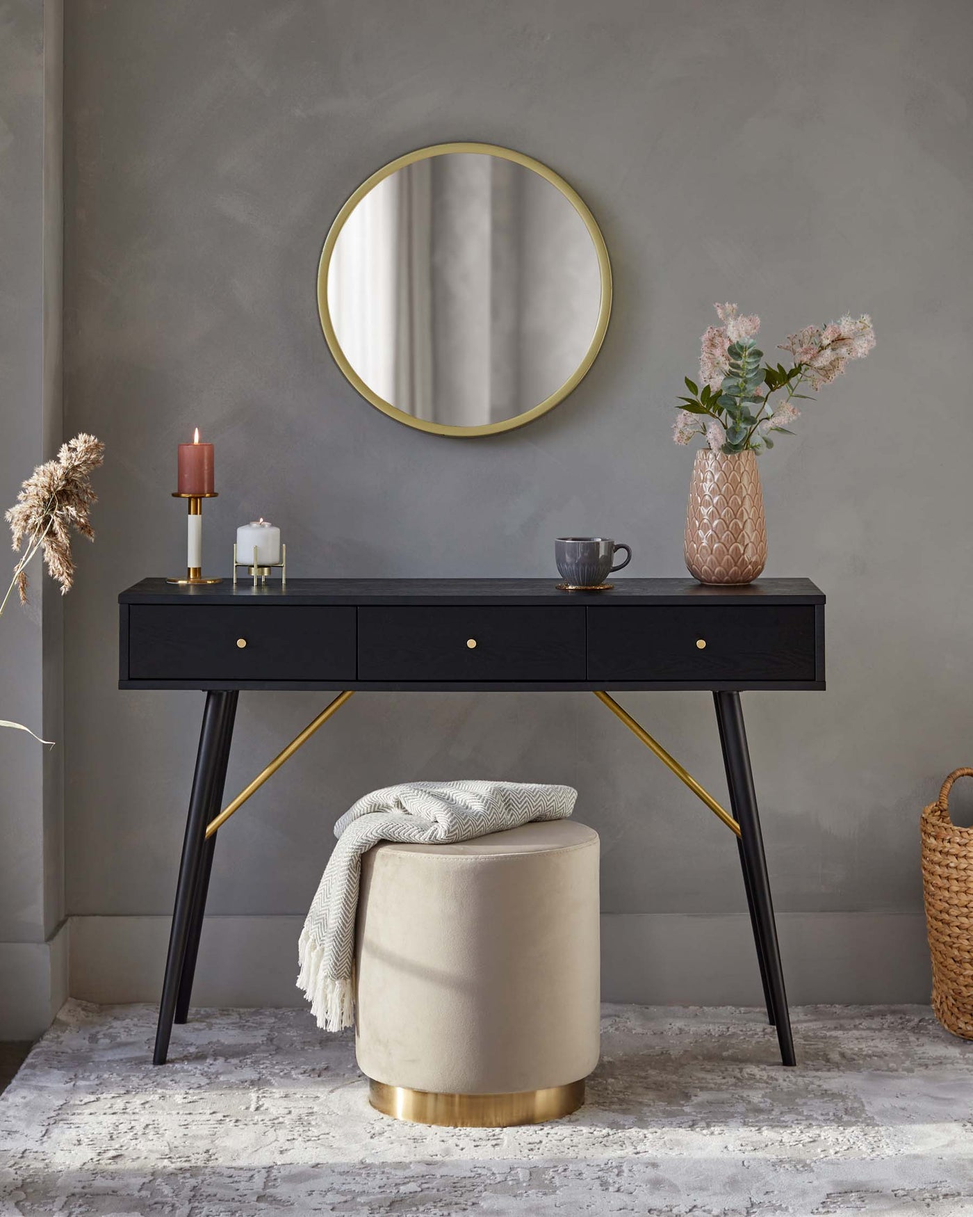 Elegant black console table with sleek brass accents and an upholstered beige round ottoman with a brass base.