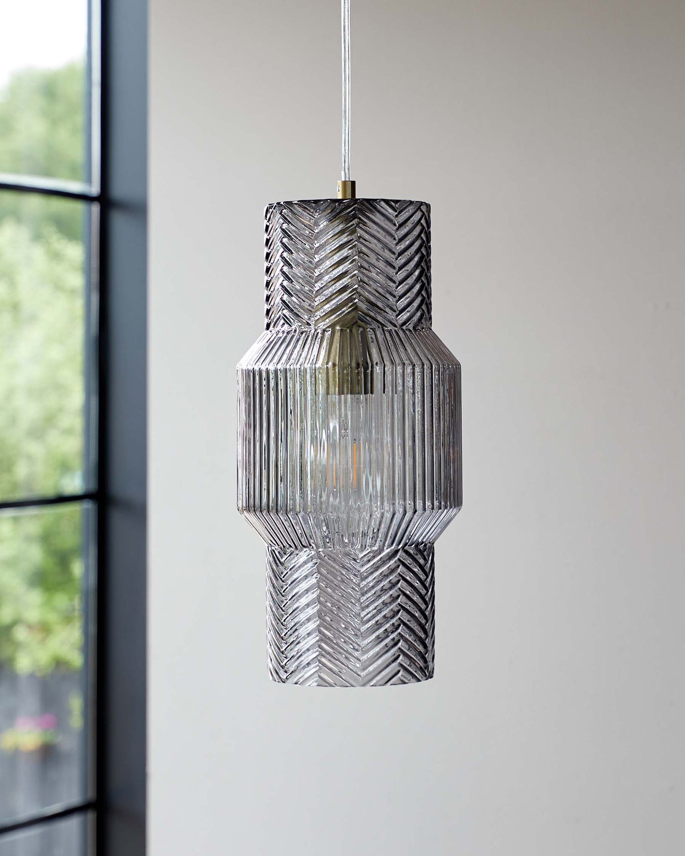 Elegant tiered glass pendant light with textured surfaces, suspended from a metallic fixture.