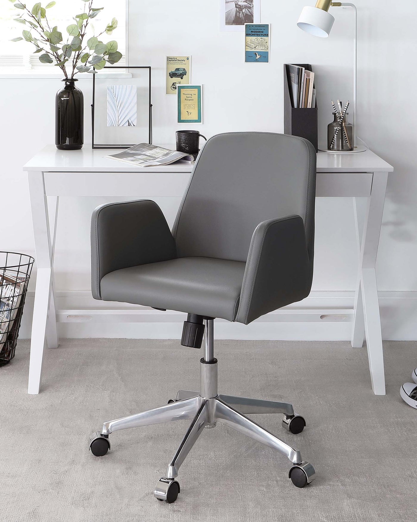 A modern white desk paired with a grey upholstered swivel office chair on casters, featuring a chrome star base.
