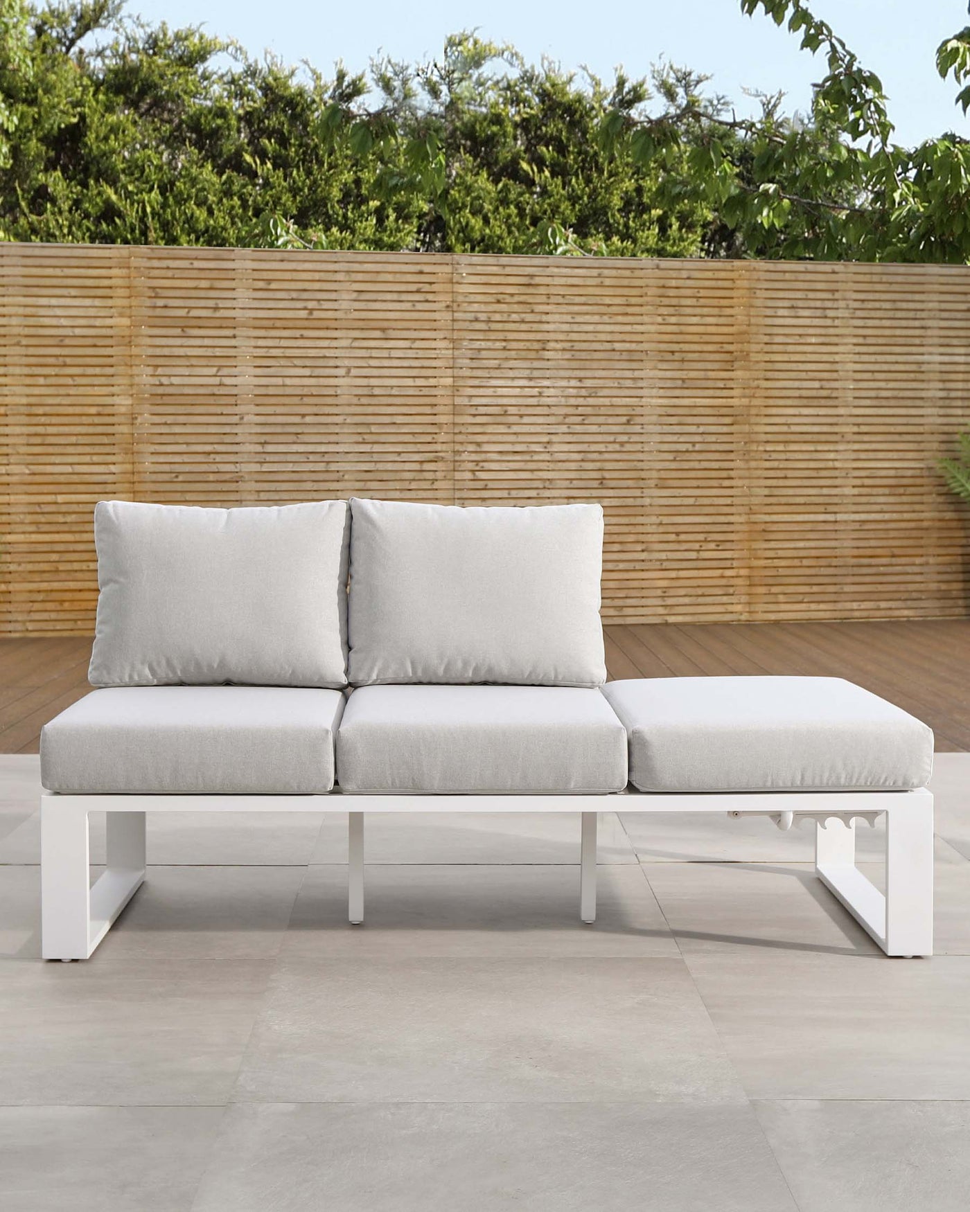 Modern white outdoor sectional sofa with light grey cushions on a patio.