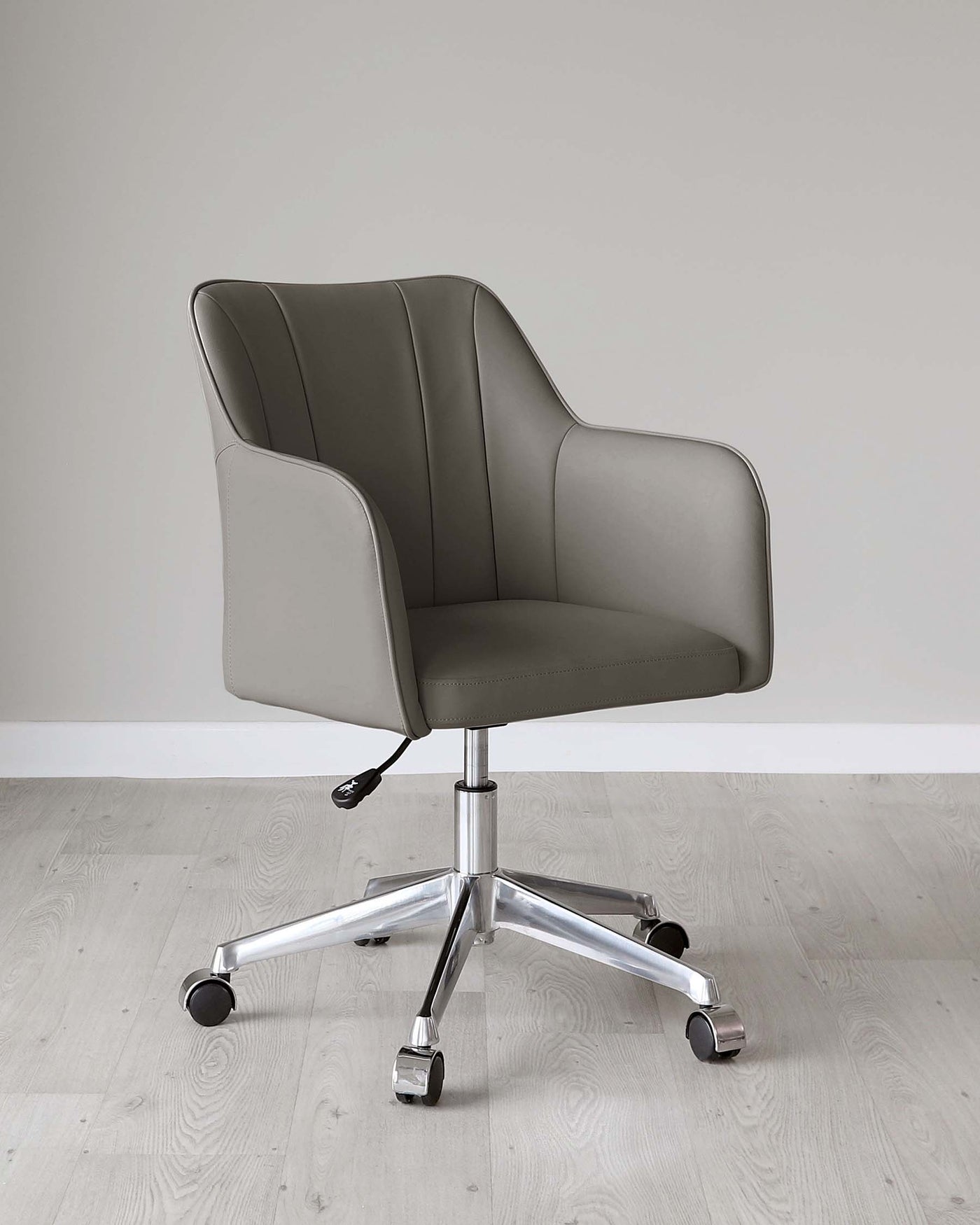 Modern office chair with a high backrest, upholstered in smooth grey fabric with subtle stitching details, featuring white piping on the edges. It is equipped with a pneumatic seat height adjustment lever on the right side. The base consists of a shiny chrome frame with five branching legs, each ending in black caster wheels for mobility. The chair is set on a light wooden floor against a clean, white background.