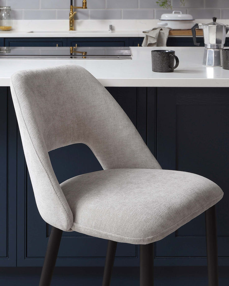 Modern light grey upholstered dining chair with a curved backrest and armless design, featuring a cut-out detail for added style. The chair is supported by four dark metal legs, creating a sleek contrast against the textured fabric. Ideal for contemporary kitchen or dining areas.