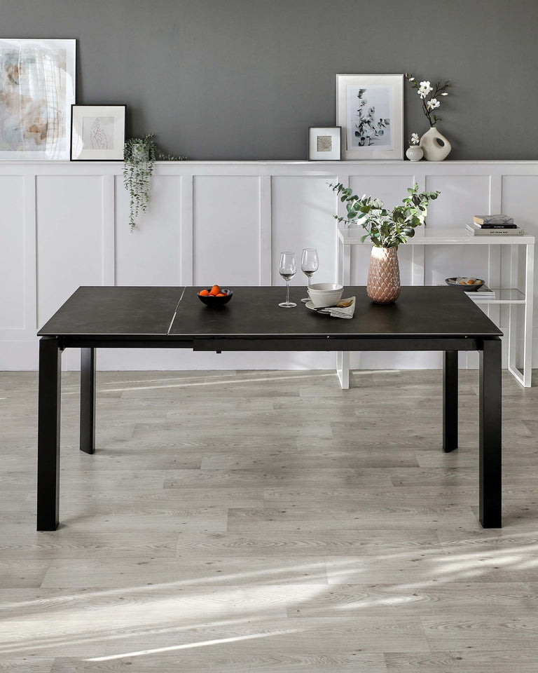 Modern black dining table with a minimalistic design and rectangular silhouette, complemented by a slim white console table against the wall.