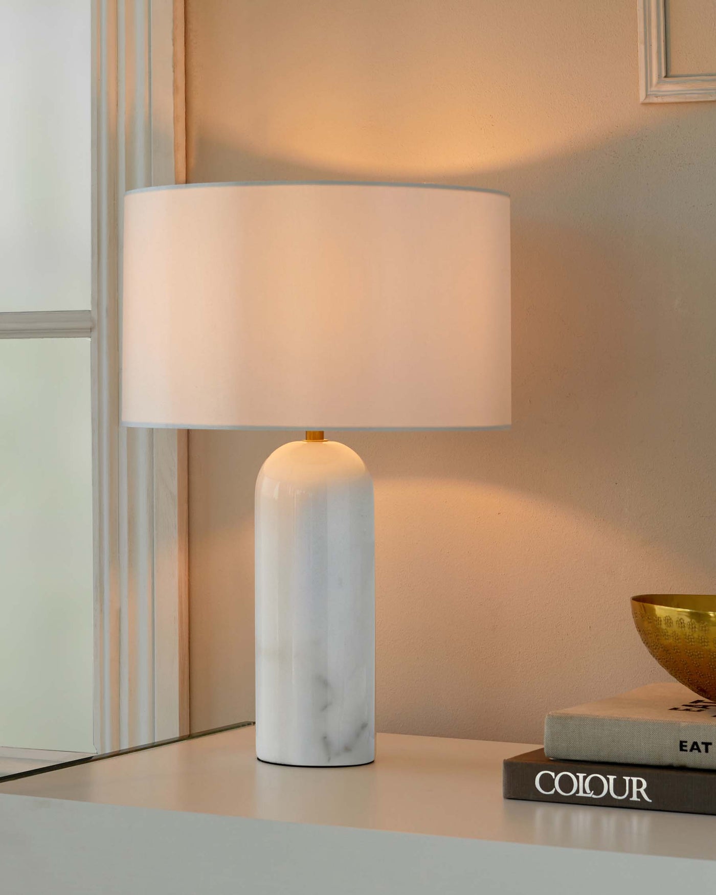 Elegant modern table lamp with a white marble base and a cylindrical cream fabric shade.