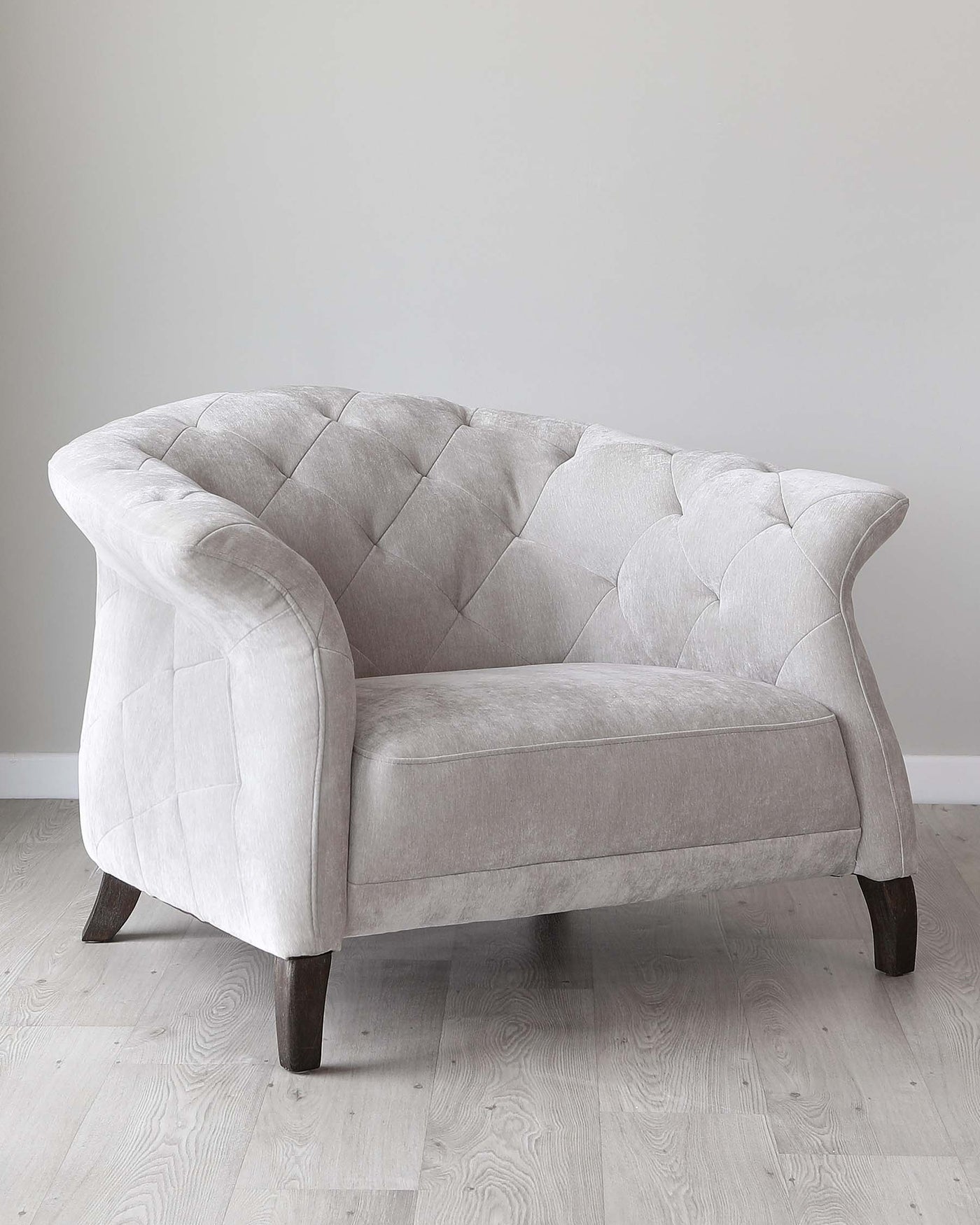 Elegant single-seater fabric sofa with a tufted backrest and curved arm design, featuring a neutral light grey upholstery and dark wooden legs.