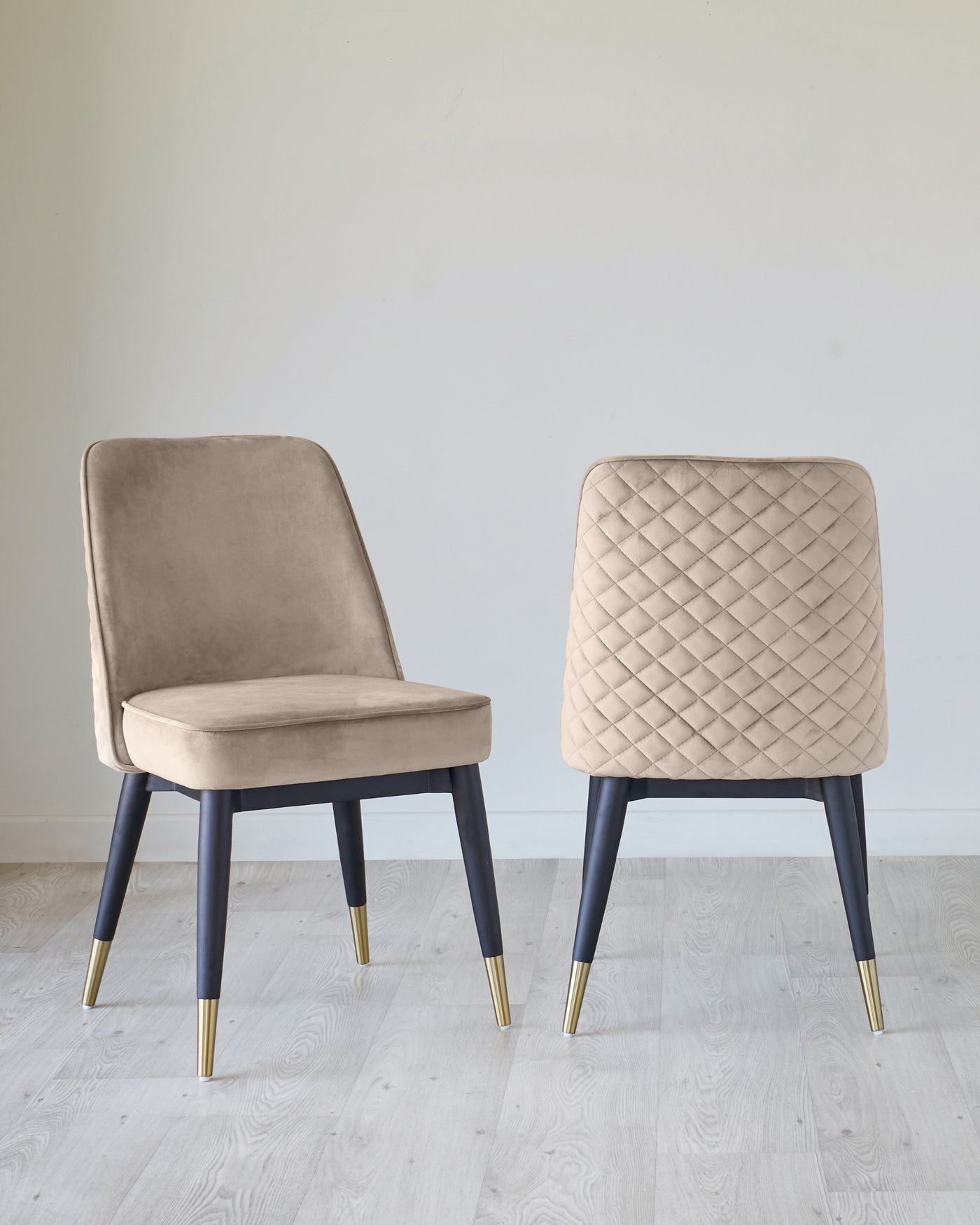 Two modern chairs with elegant design, featuring beige upholstery and dark tapered legs with gold-coloured tips. The chair on the left has a smooth, softly curved backrest, while the chair on the right boasts a textured, diamond-patterned backrest.