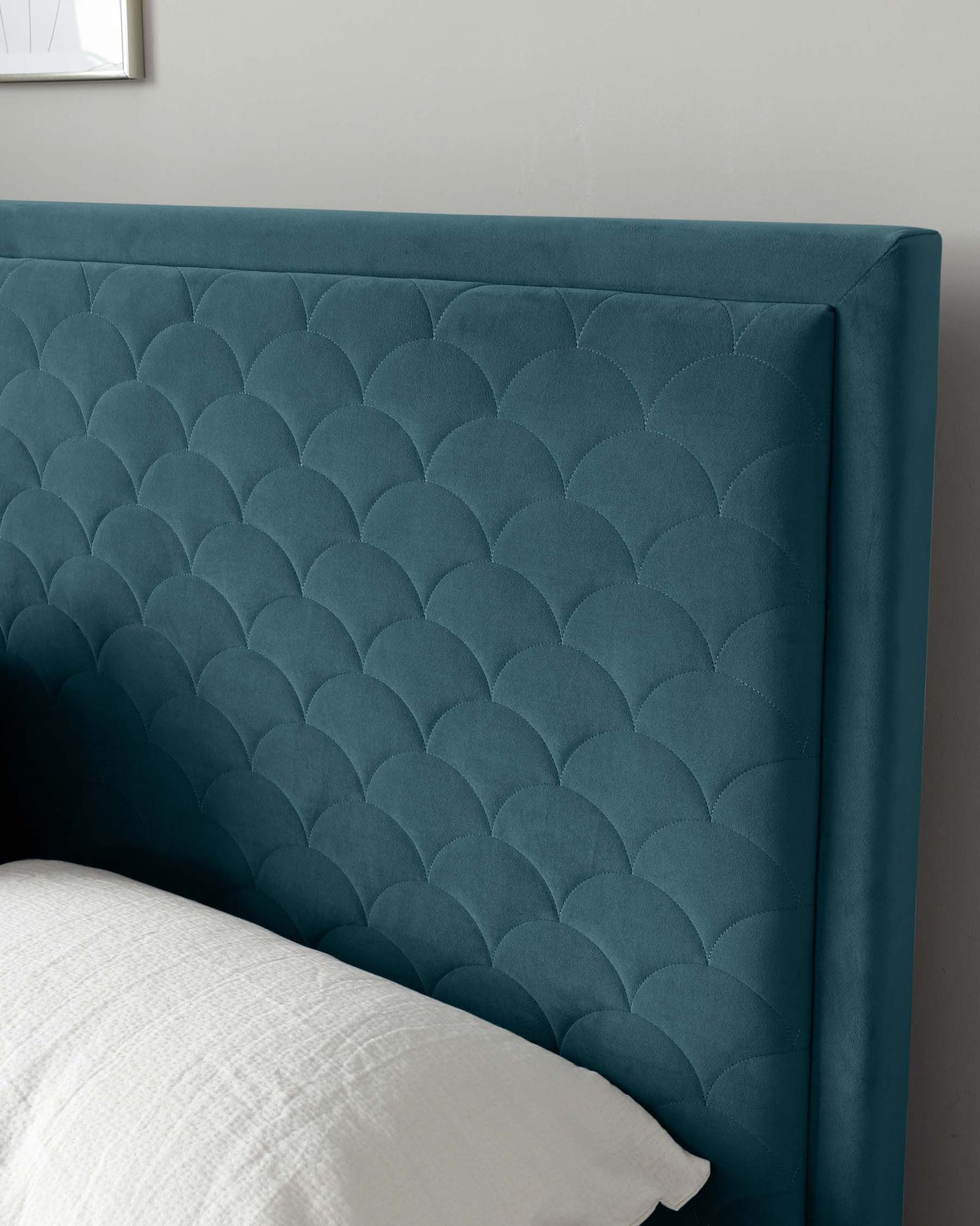 Elegant teal upholstered headboard featuring a scalloped silhouette with deep diamond tufting, paired with a white pillow in a tidy bedroom setting.