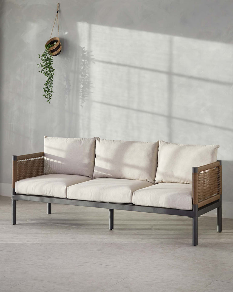 A modern three-seat sofa with a minimalist metal frame and woven side panels. The sofa features thick, plush cushions in a light neutral tone, providing a contrast to the sleek dark frame. The design is simple yet elegant, suitable for contemporary interior styles.
