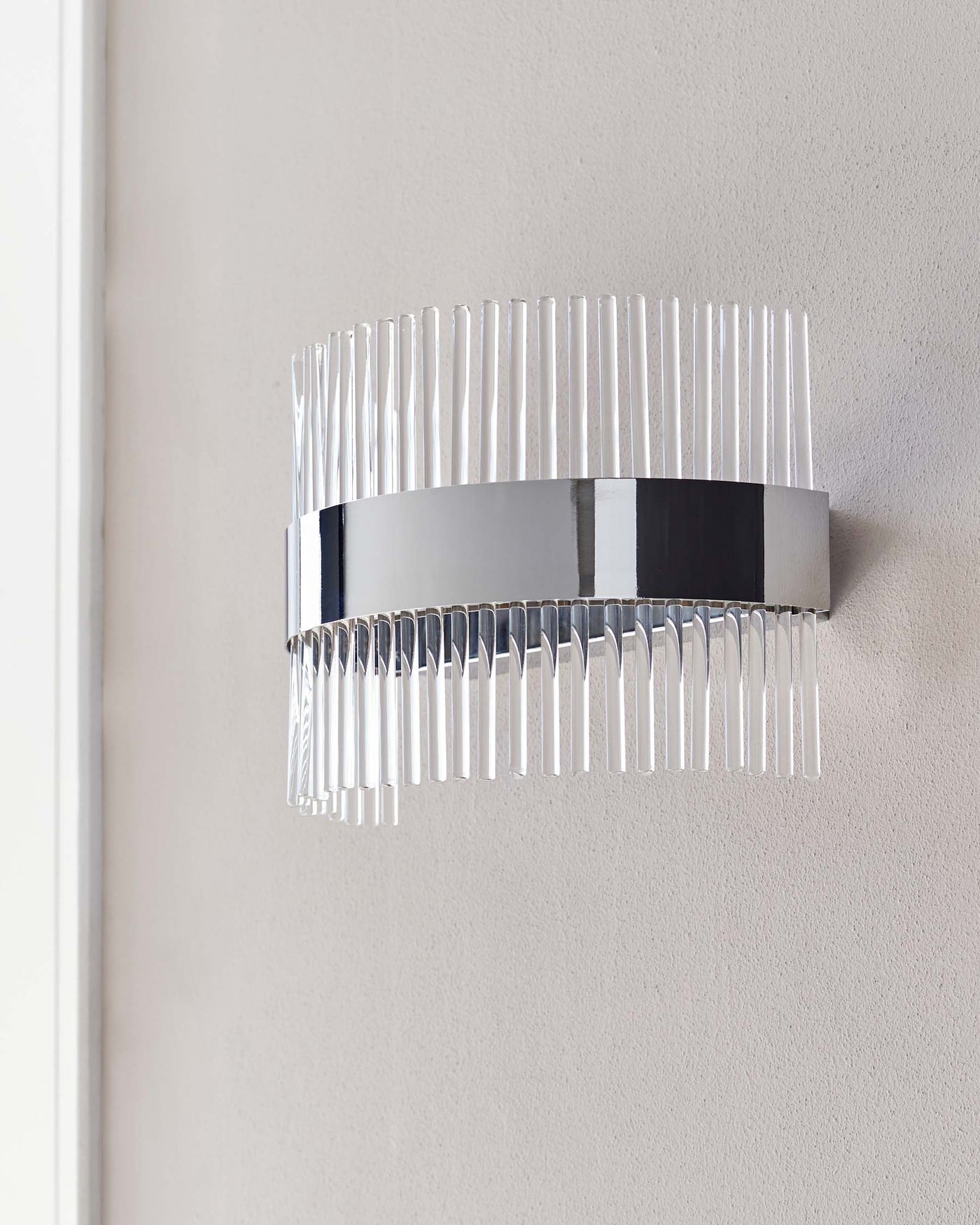 Modern wall-mounted light fixture with a chrome finish and clear glass prisms, creating a luxurious and contemporary ambiance.