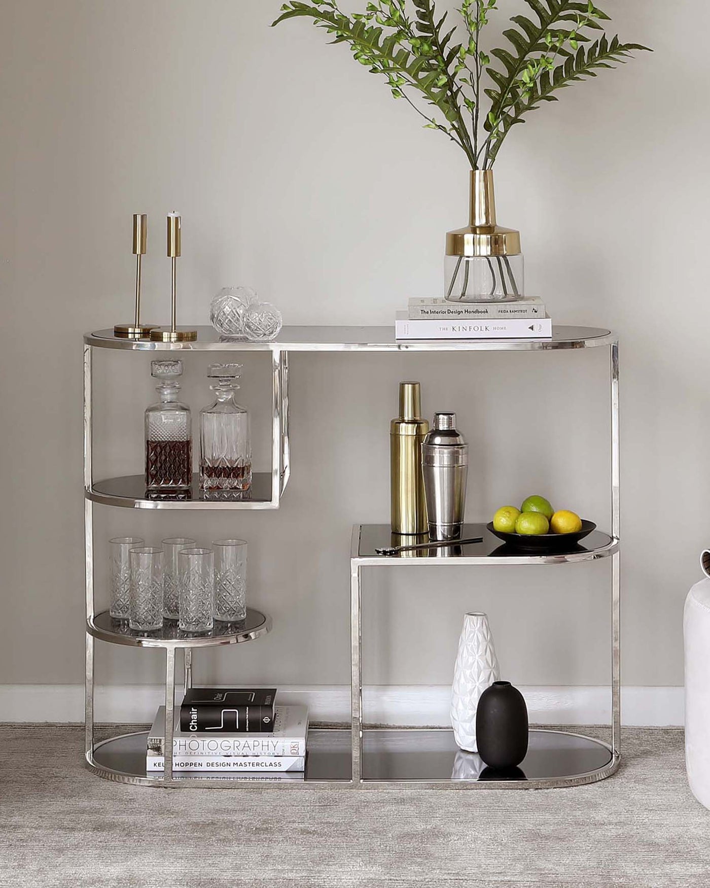 Contemporary circular silver-finished metal shelving unit with three tiers, featuring reflective mirrored shelves at varying heights.