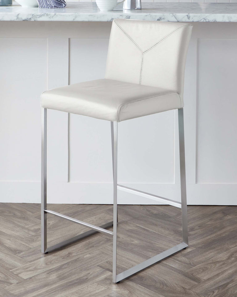 Modern bar stool with a light beige, leather-like upholstered seat and backrest, featuring a geometric stitch pattern on the back, complemented by a sleek chrome-finished metal frame with a simple footrest.