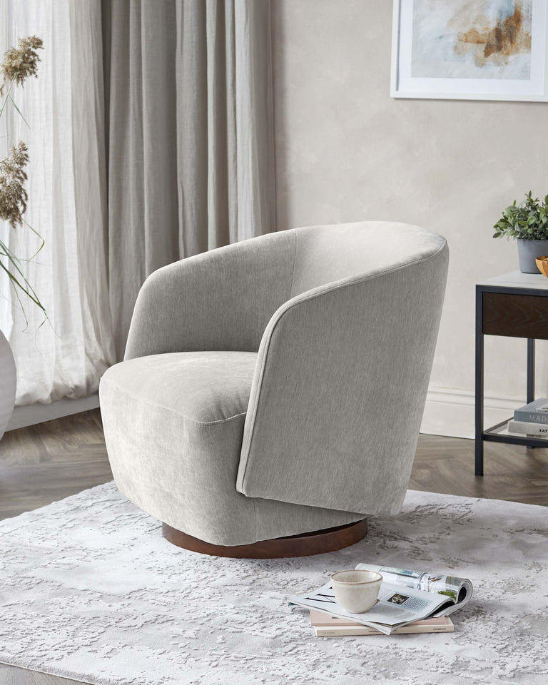 A modern, light grey upholstered swivel armchair with a smooth, curved backrest and a rounded seat, set on a dark wooden circular base. The chair is positioned on a textured white area rug with a small side table and framed artwork in the background, enhancing the contemporary aesthetic of the room.