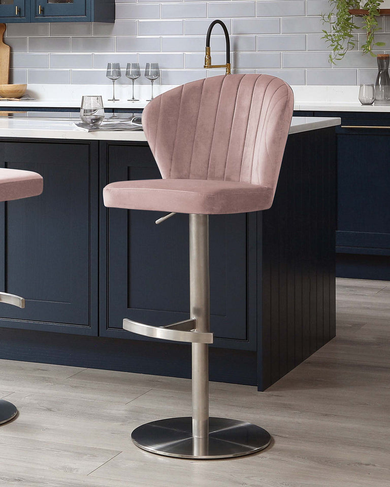 Elegant modern bar stool with a plush, blush pink velvet upholstered seat featuring vertical channel tufting. The stool has a curved backrest, a round, stable brushed metal base, and a convenient footrest, seamlessly adjustable with a gas-lift mechanism.