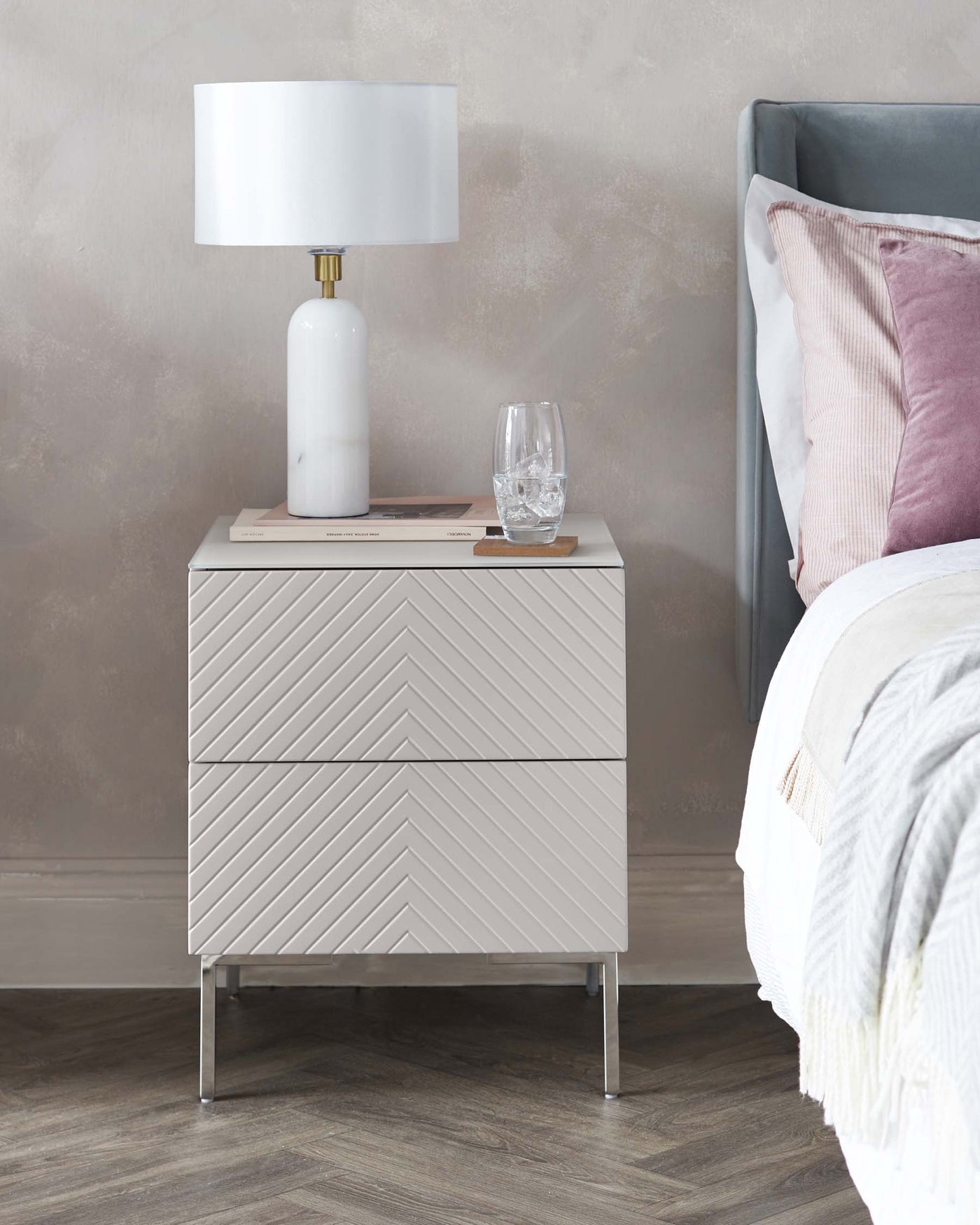 Modern bedside table with chevron design in a light wood finish, featuring a single drawer with a sleek black handle and metal legs.