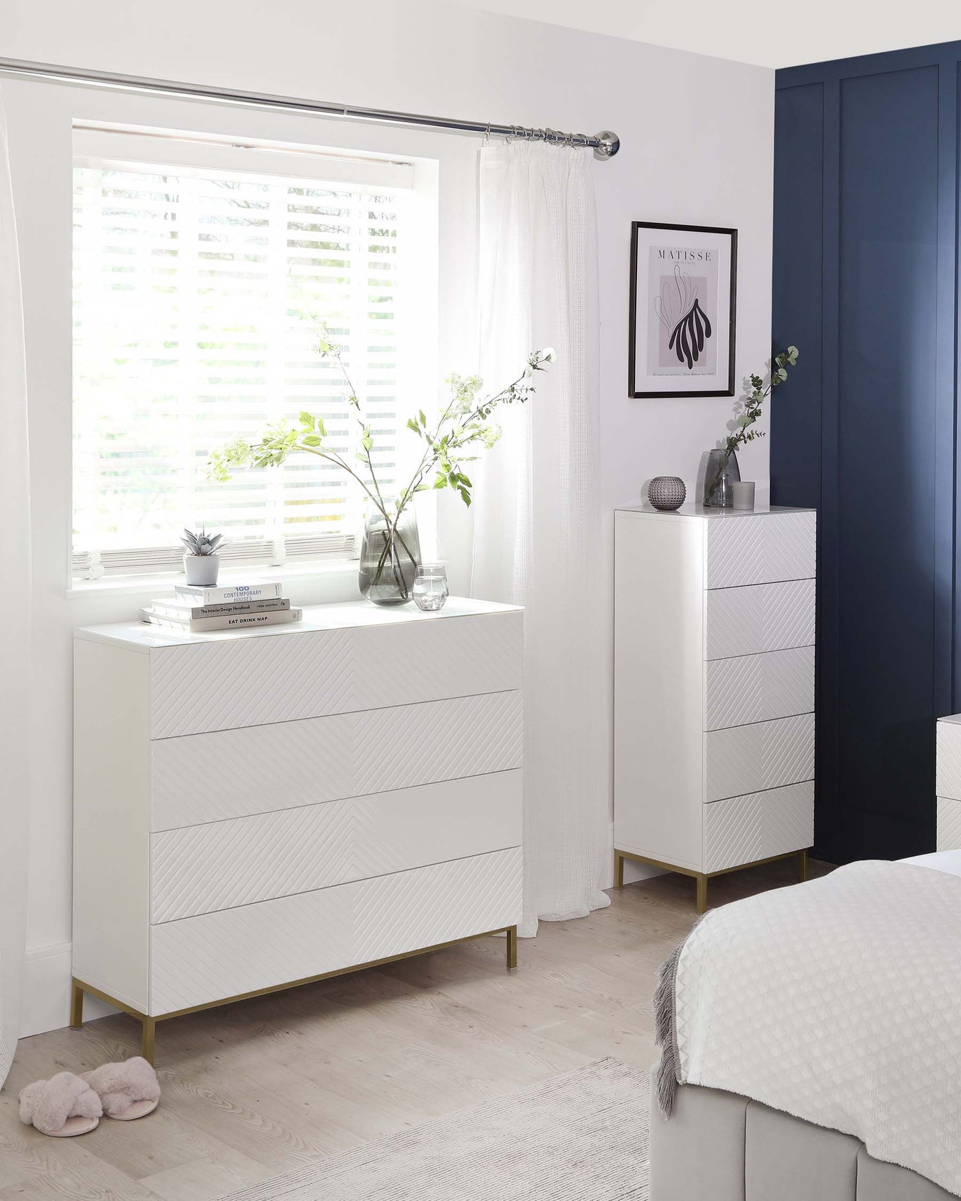 Elegant white bedroom furniture comprising a six-drawer dresser and a five-drawer chest, both with a textured front and brass accents at the base.
