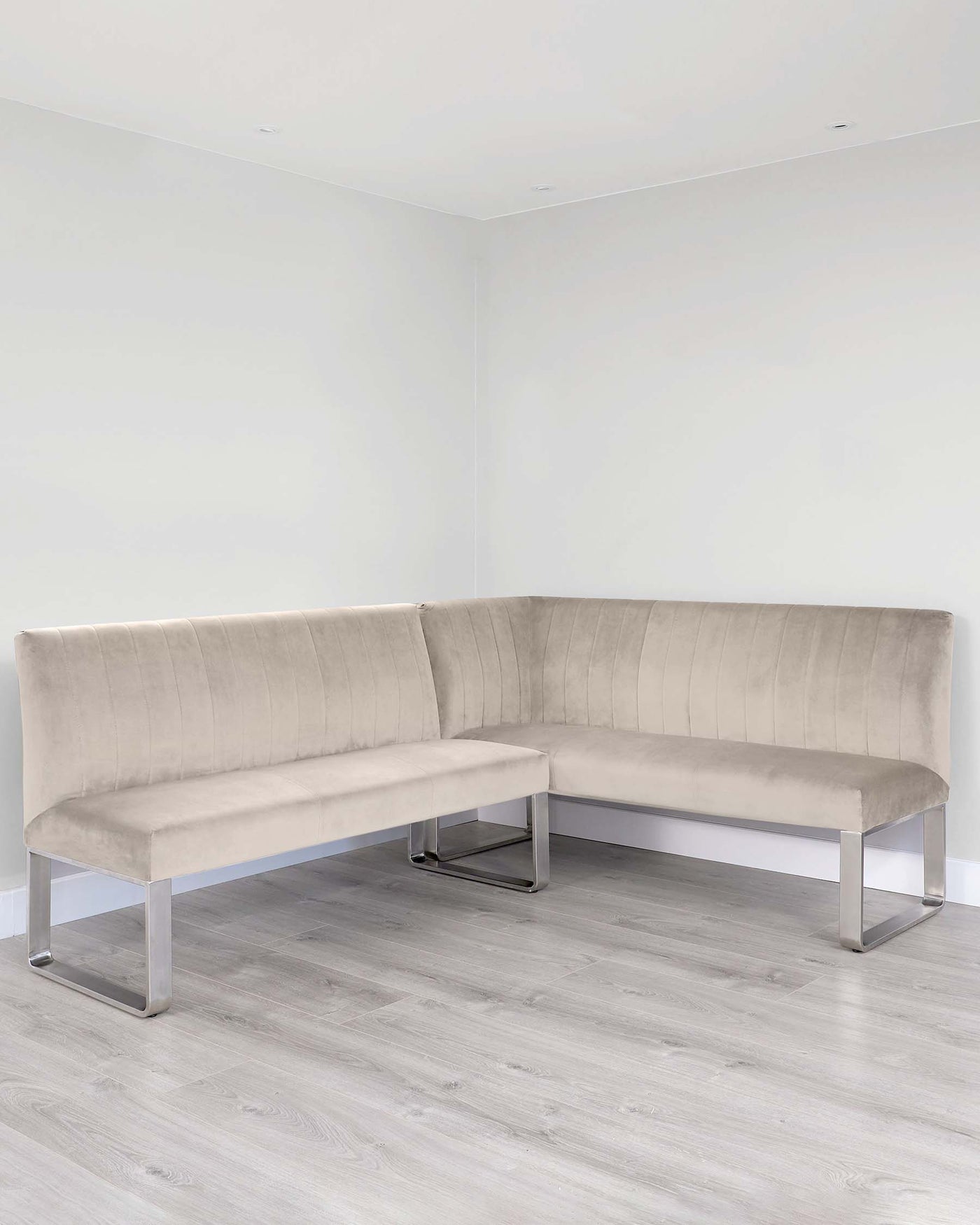 L-shaped sectional sofa with a contemporary design, featuring plush backrests with vertical stitching, an upholstered seat in a light beige fabric, and sleek metallic legs.