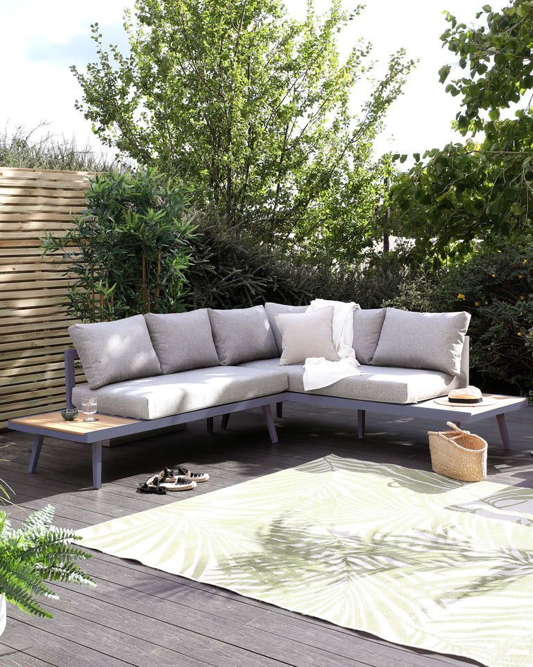 Contemporary outdoor sectional sofa with light grey cushions on a sleek wooden frame with an attached side table, set on a patterned area rug with botanical design, in a cosy garden patio setting.