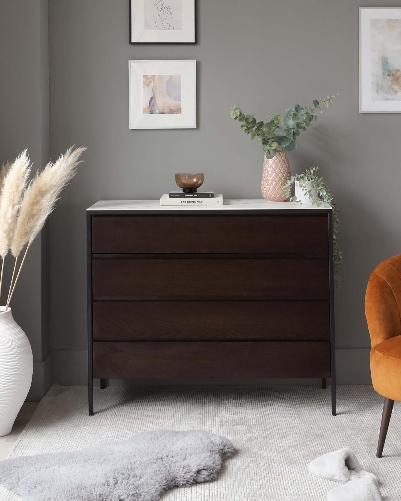 A modern dark-brown wooden dresser with three drawers, featuring sleek handles and angled legs.