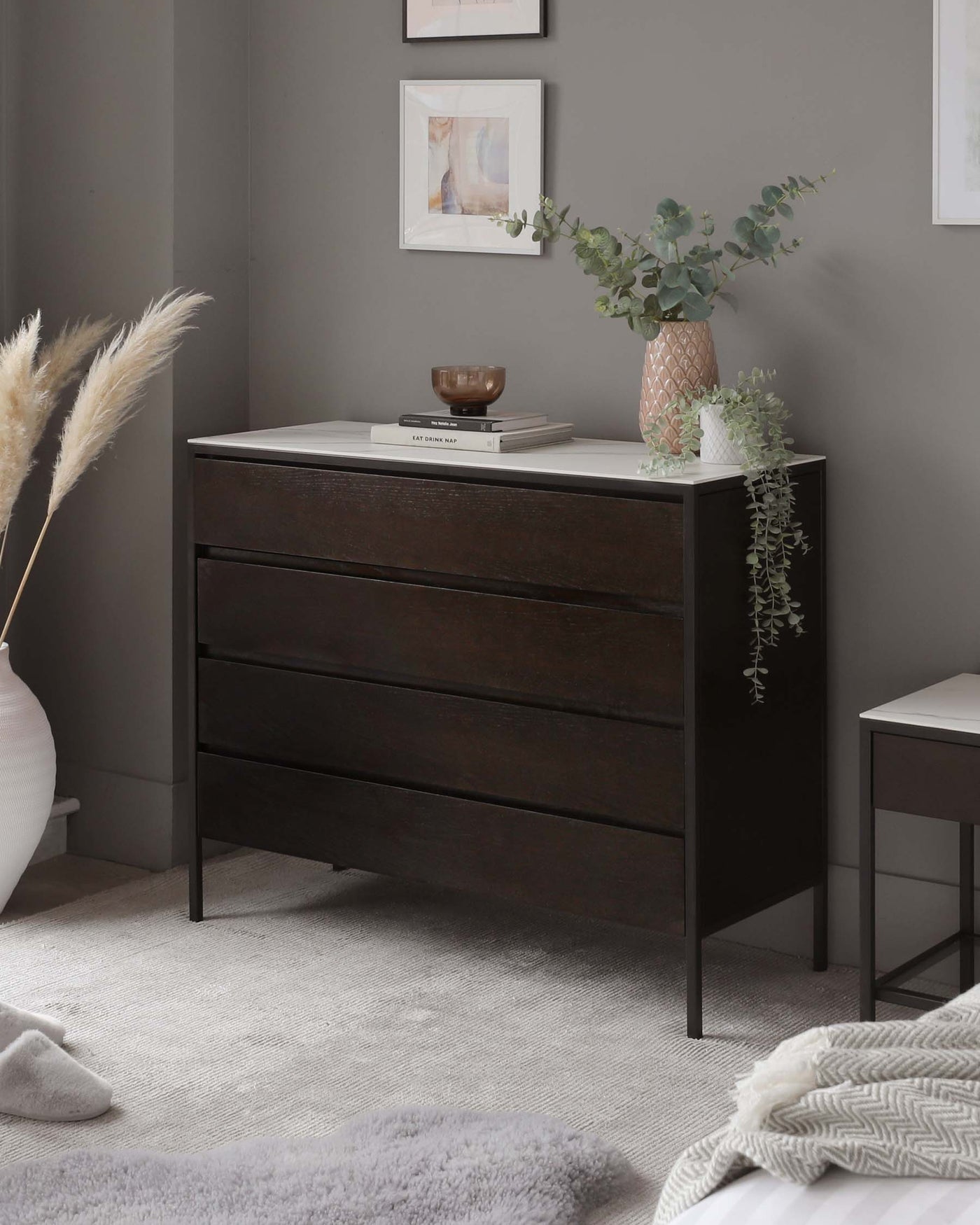 Modern espresso brown three-drawer dresser with a minimalist design and sleek black metal handles, complemented by a small, square black side table with a simple frame structure.