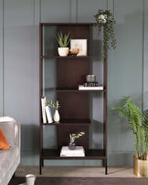 Five-tiered, dark wood and metal bookshelf with asymmetrical shelves, styled with books, decorative plants, and vases.