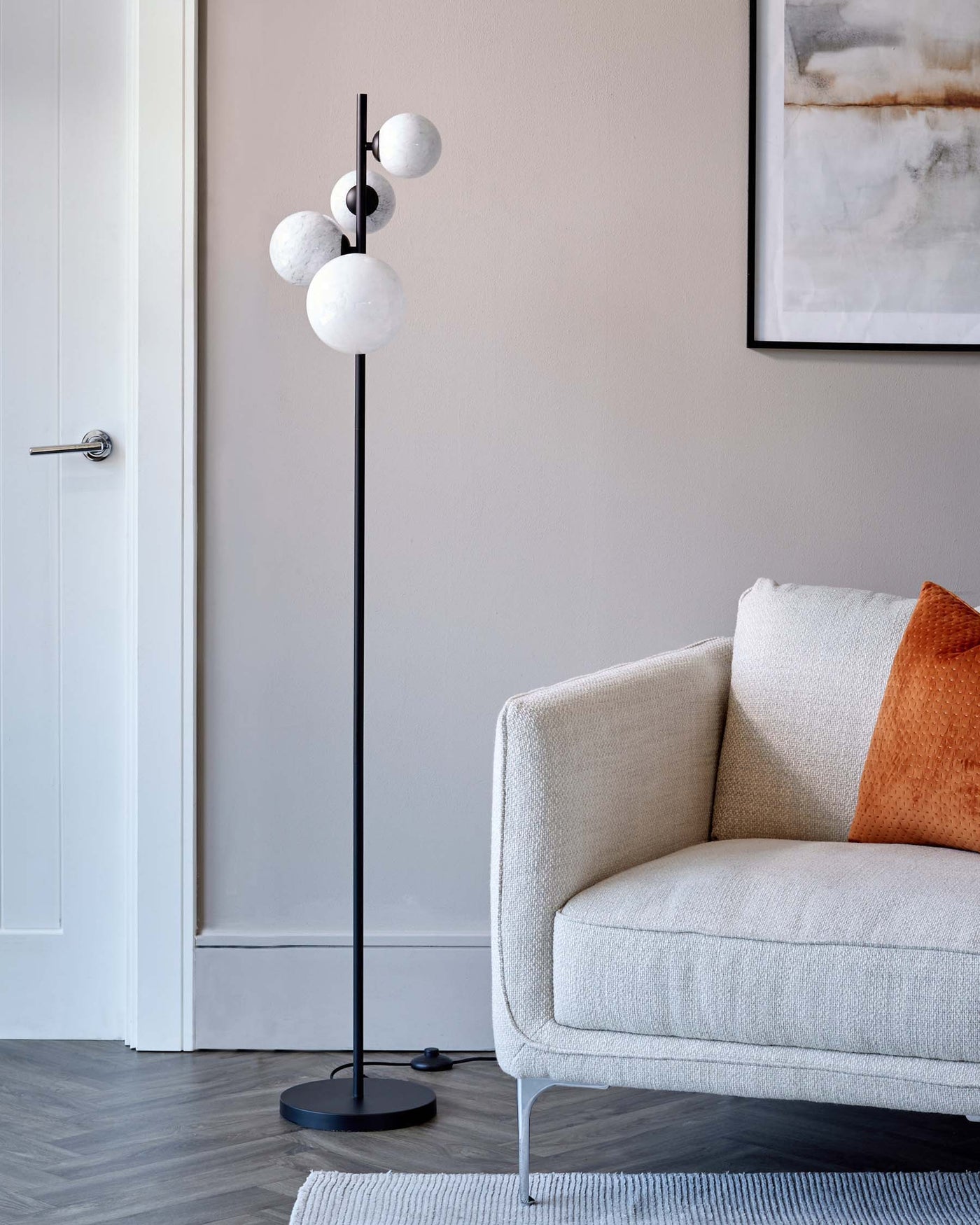 Modern interior with a minimalist white fabric upholstered armchair and a stylish floor lamp featuring a black stand and spherical white shades.