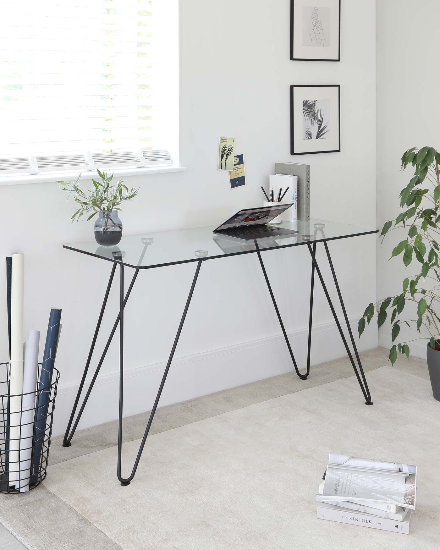 Modern minimalist glass-top desk with black metal hairpin legs.