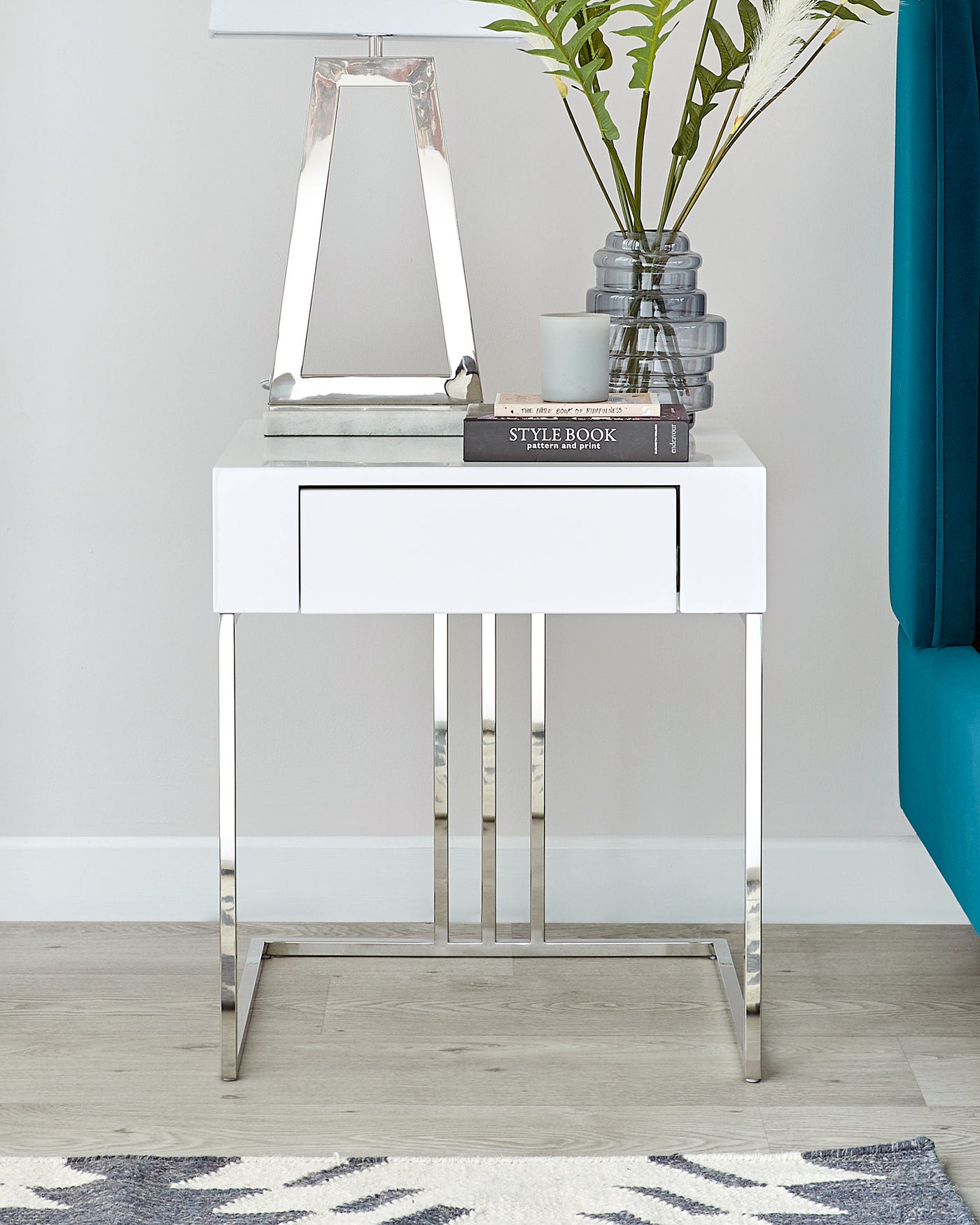 Modern white console table with a sleek design, featuring a glossy finish, one drawer with a silver handle, and slim stainless steel legs in a minimalist style.