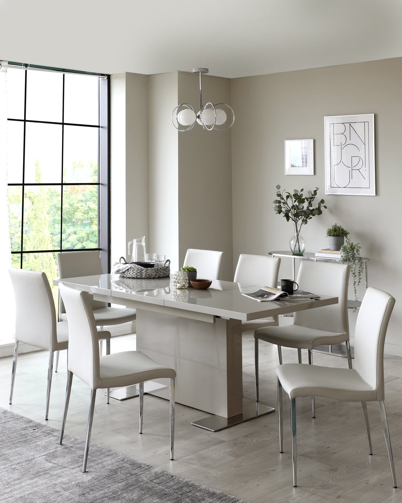 Modern dining room with a rectangular high-gloss finish table and six sleek white leather upholstered chairs with thin chrome legs. A grey area rug lies underneath.