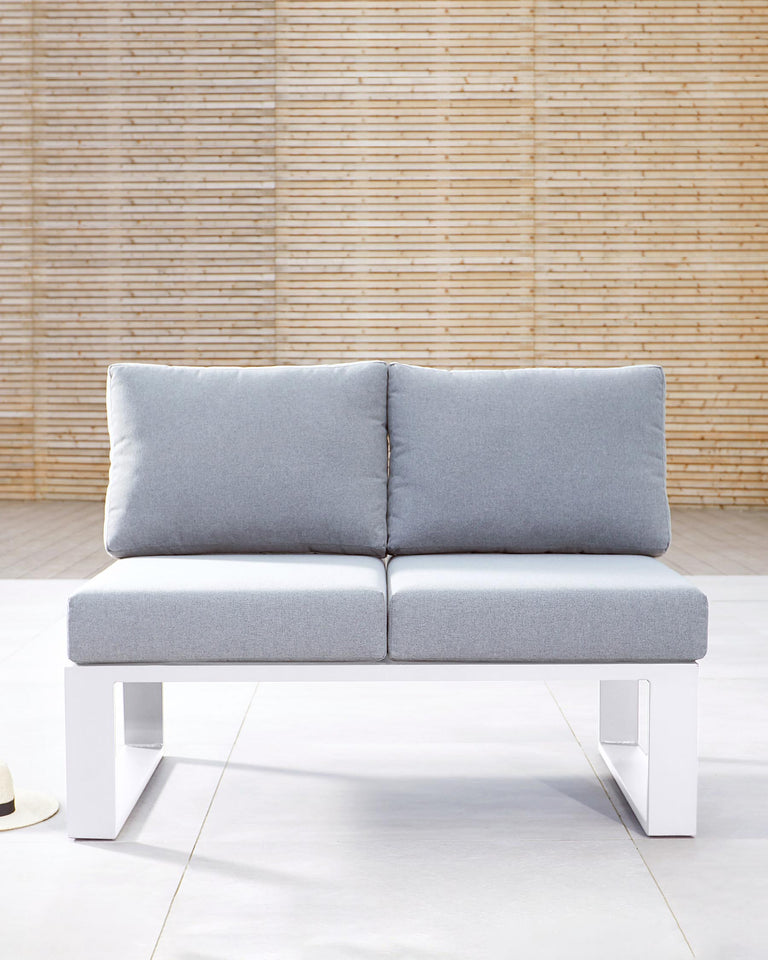 A modern minimalist two-seater sofa with a clean design, featuring a solid white base and light grey cushions. The base has a distinctive U-shaped silhouette that supports a pair of thick, comfortable seat cushions and two backrest cushions, all upholstered in a light grey fabric. The couch is showcased against a textured bamboo wall, suggesting a contemporary and natural ambiance.