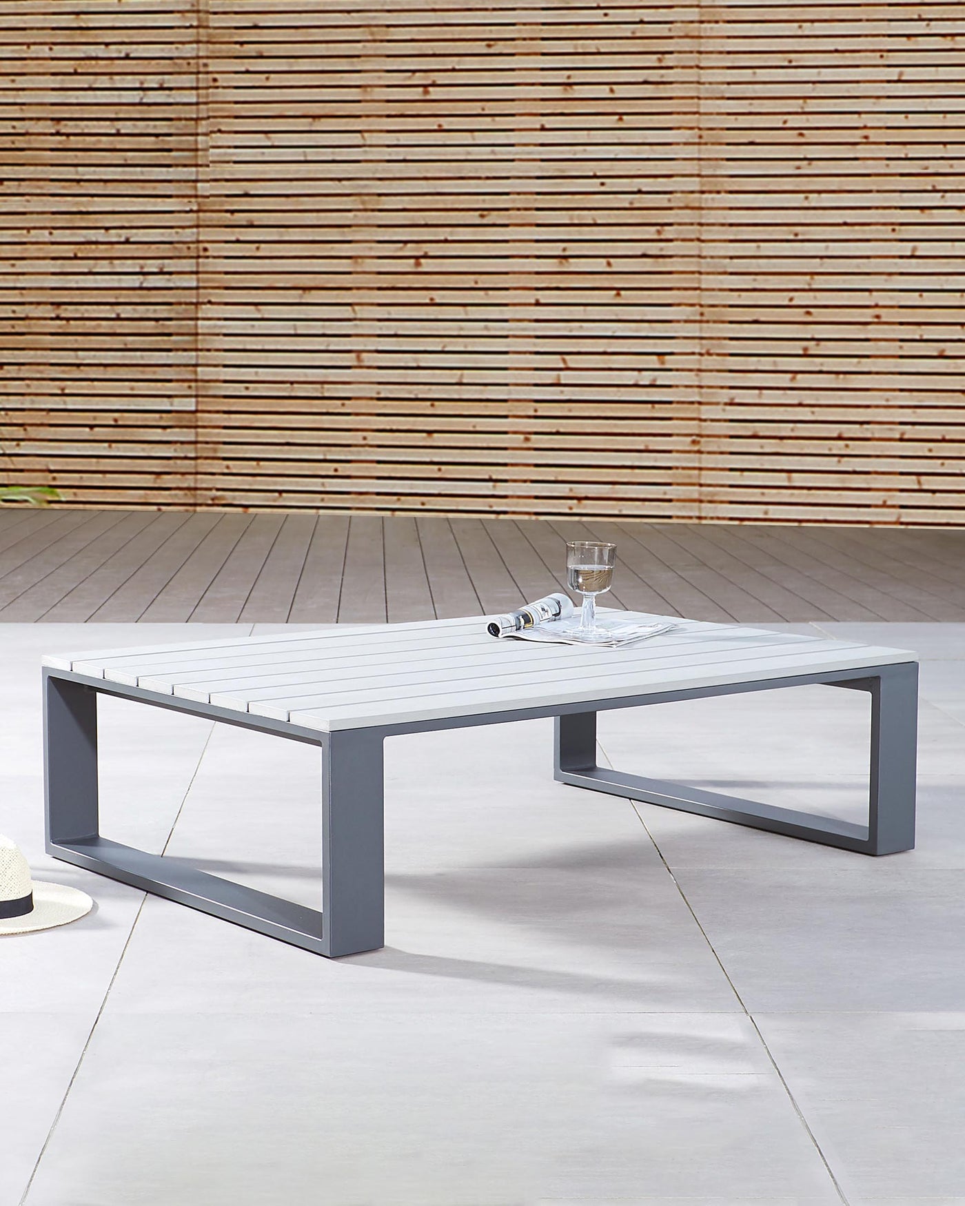 Modern low-profile outdoor coffee table with a white slatted tabletop and a minimalist grey metal frame.