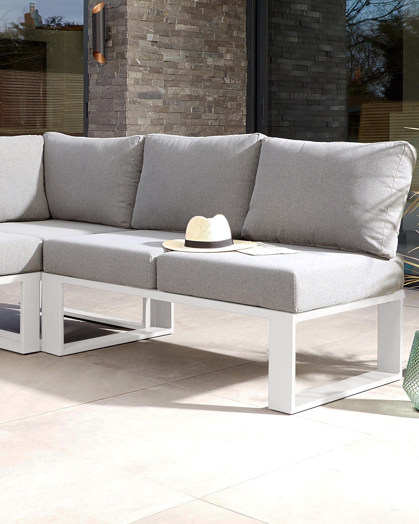 Modern outdoor sectional sofa with light grey cushions on a white minimalist frame, accompanied by a white square side table.