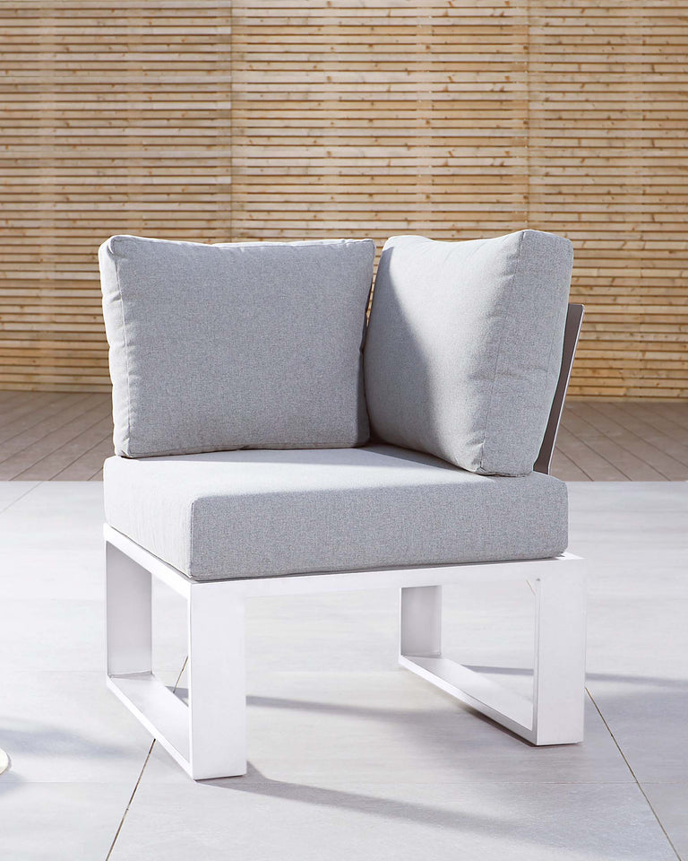 Modern white outdoor armchair with grey cushions against a bamboo backdrop.