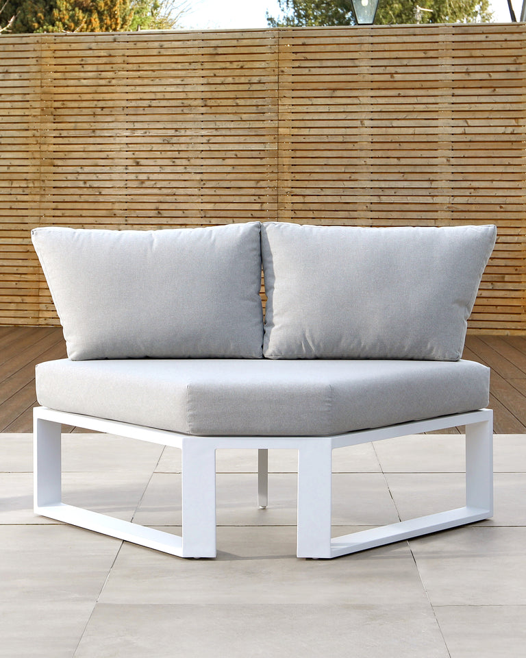 Modern outdoor corner sofa piece with a white minimalist frame and light grey cushions, featuring a large back cushion and a smaller rectangular side cushion.