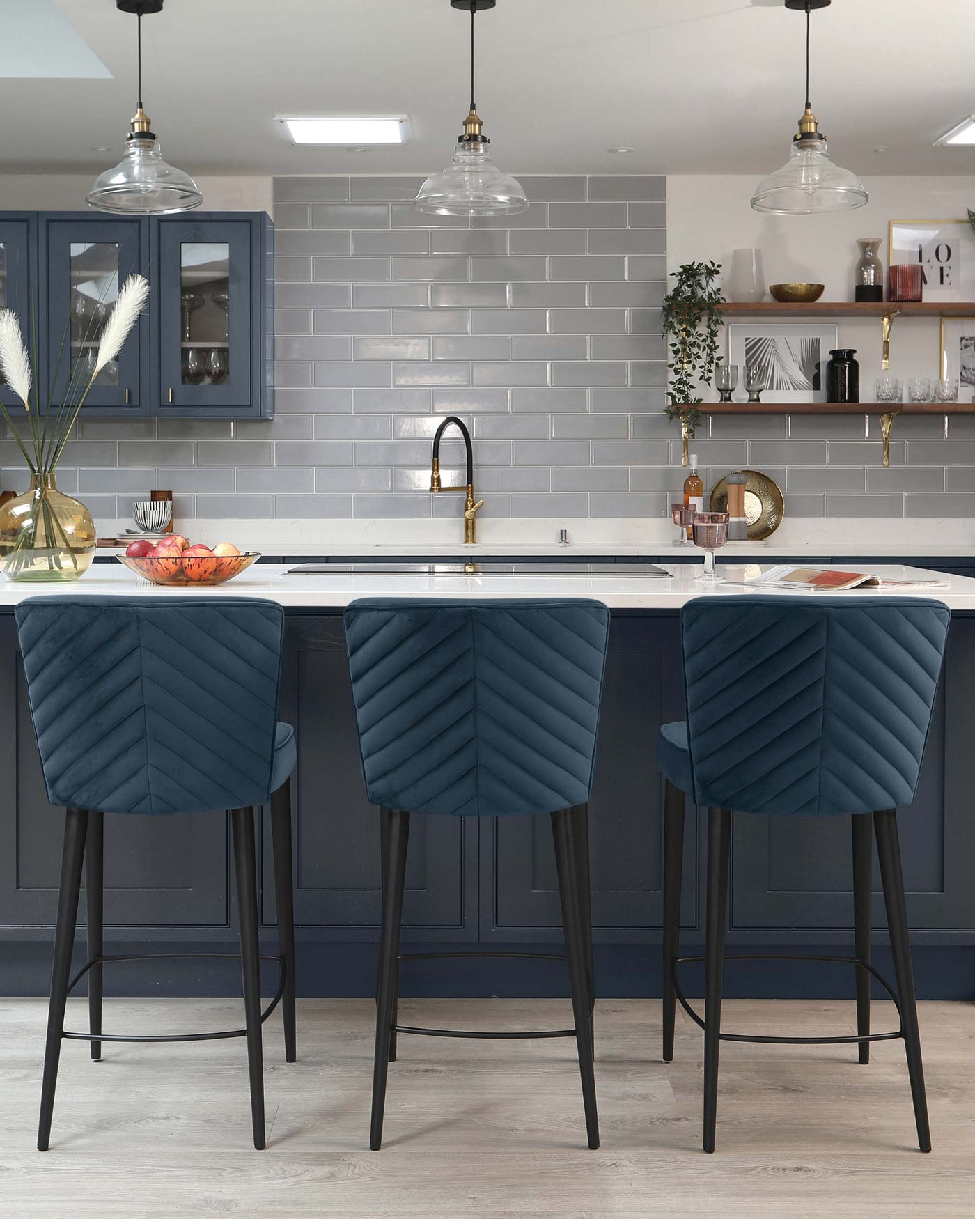 Elegant modern kitchen bar stools with plush, quilted navy-blue upholstery and sleek black legs.