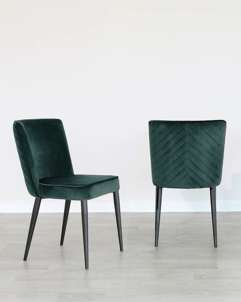 Two modern green velvet dining chairs with black metal legs, one showing the front view and the other showing the back view, featuring a geometric chevron pattern, set against a white wall and light wood flooring.