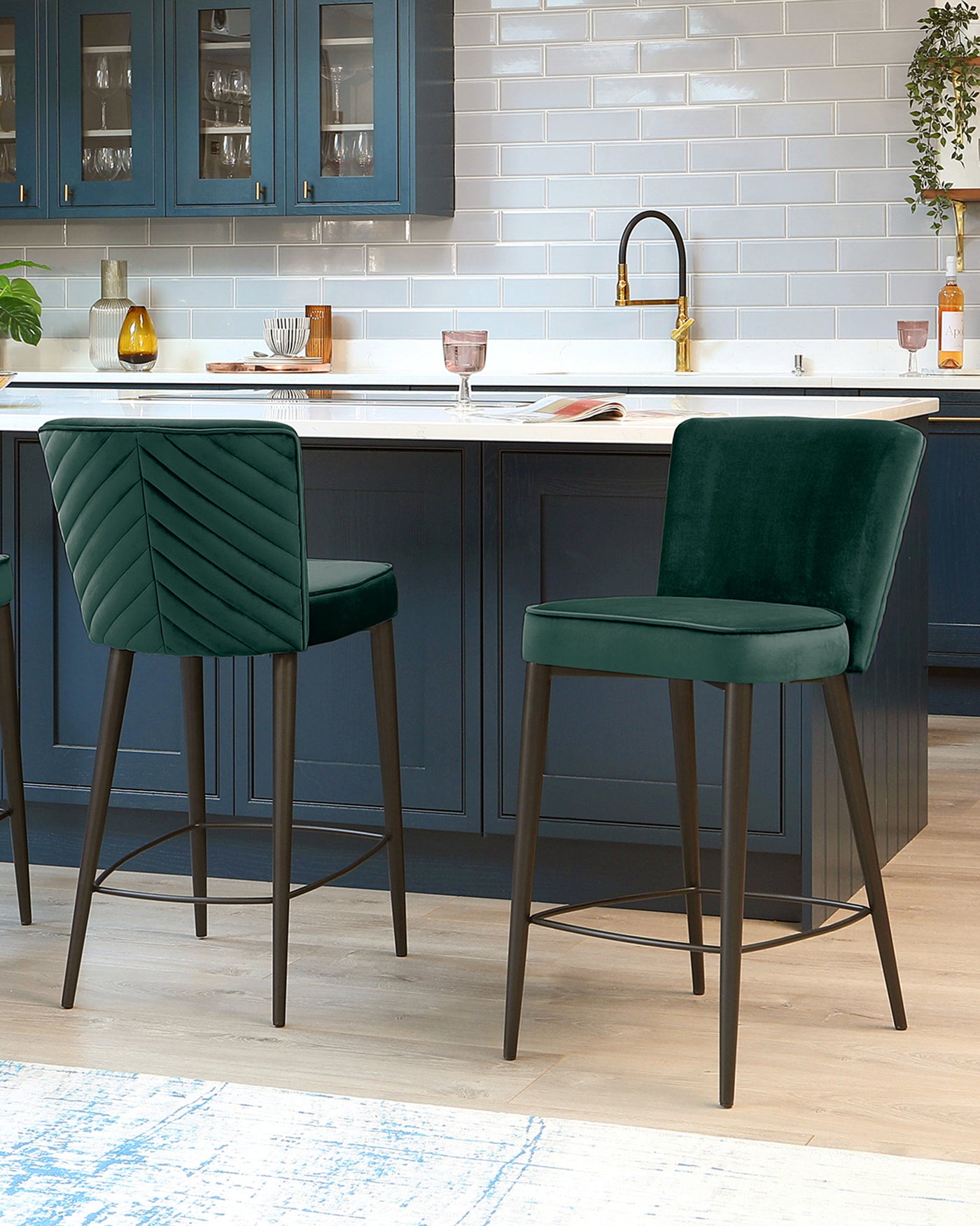 Two elegant green velvet bar stools with diamond tufting and sleek black metal legs, positioned at a kitchen island.