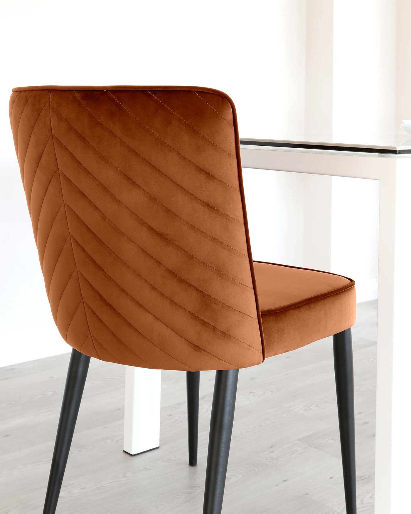Modern dining chair with a caramel brown upholstered seat and quilted backrest, paired with black metal legs.