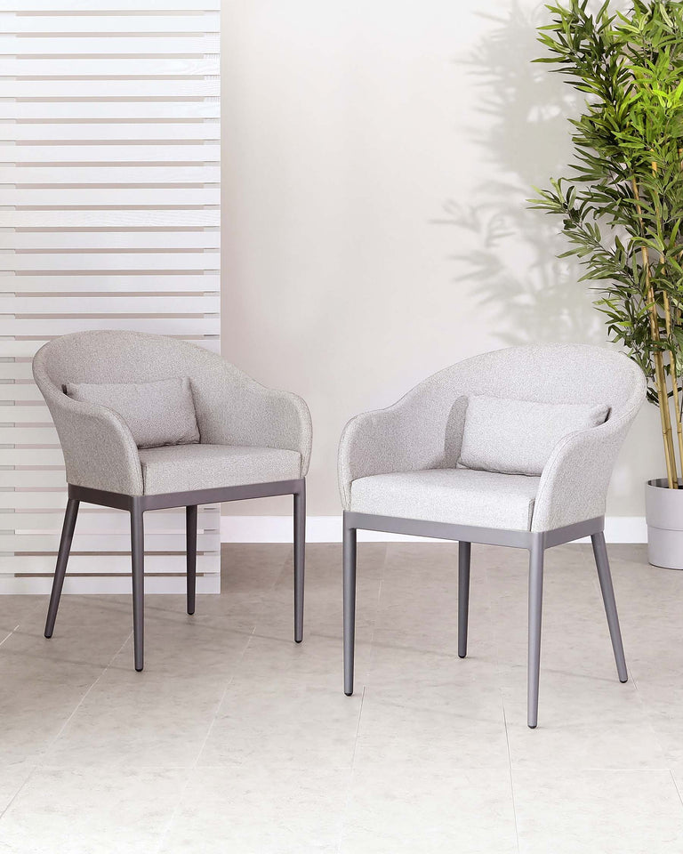 Two contemporary armchairs with light grey fabric upholstery and sleek metallic legs, set in a clean and modern indoor space with minimalist decor.