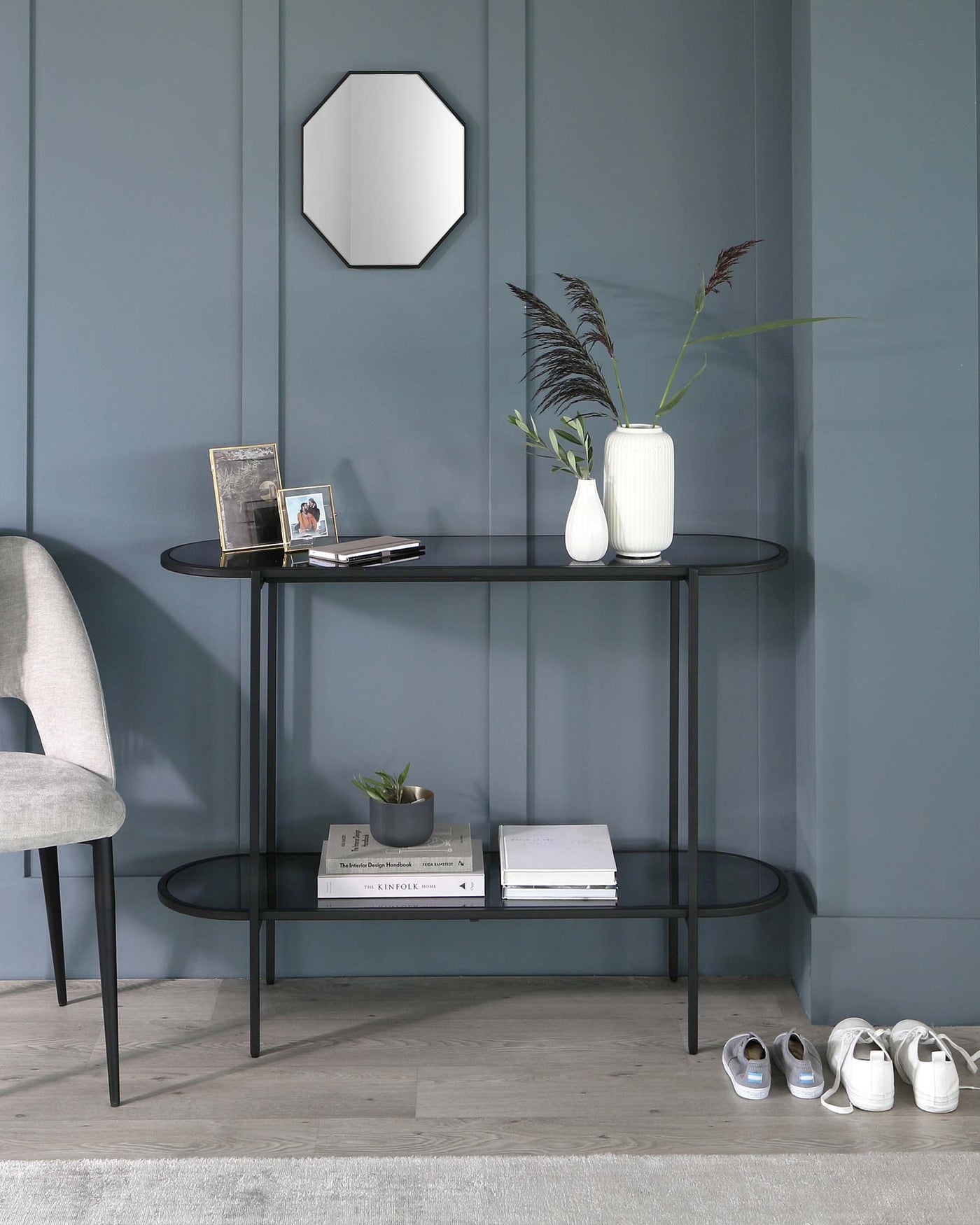 Minimalist black metal console table with two oval-shaped tiers, featuring a smooth matte finish and sleek lines. Perfect for displaying decor and storing books or daily essentials.