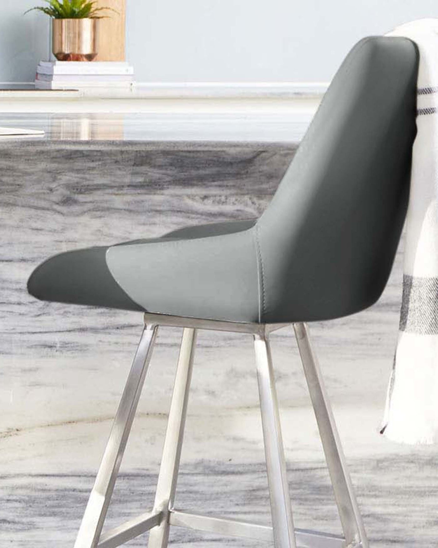 Modern grey upholstered bar stool with a sleek silhouette and metallic silver legs.