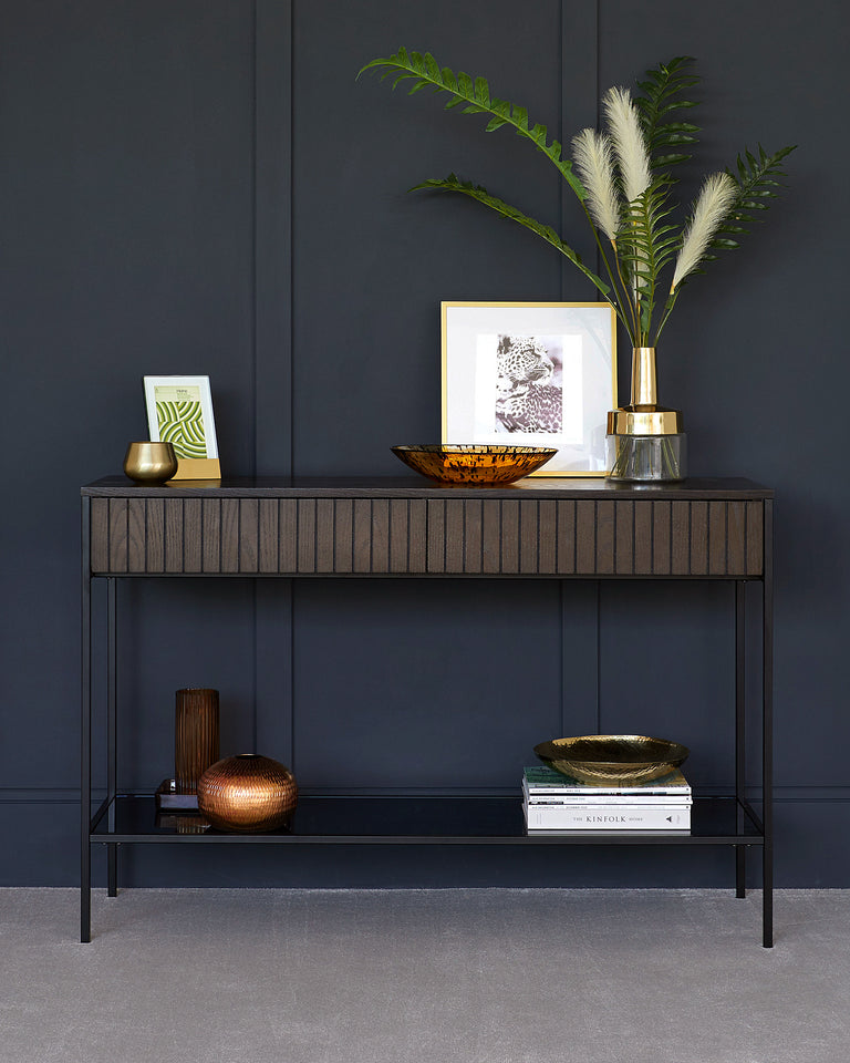 Elegant modern console table with a slim metal frame and a dark wood top featuring ribbed detailing, displaying decorative items and books on its surface and lower shelf.