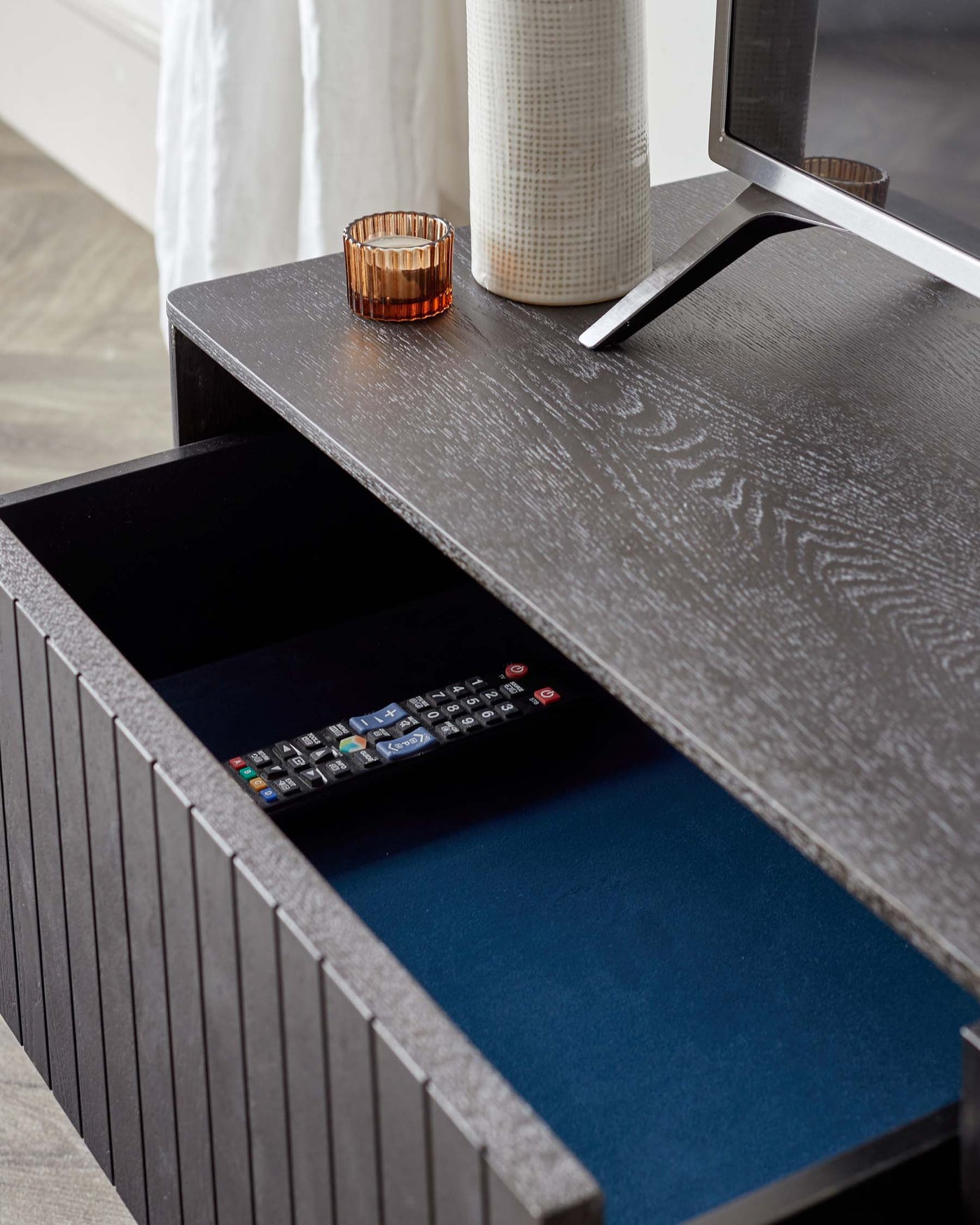 Contemporary dark wood textured side table with a pull-out drawer lined with blue felt, showcasing a minimalistic design and a sleek, modern metal drawer handle.