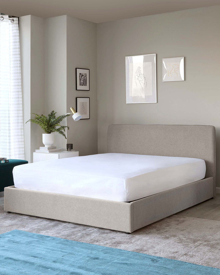 Modern minimalist upholstered platform bed with a sleek, low-profile design in a neutral grey fabric, accompanied by a white nightstand featuring clean lines and a simple aesthetic. A teal ottoman with a velvety texture adds a pop of colour to the space.
