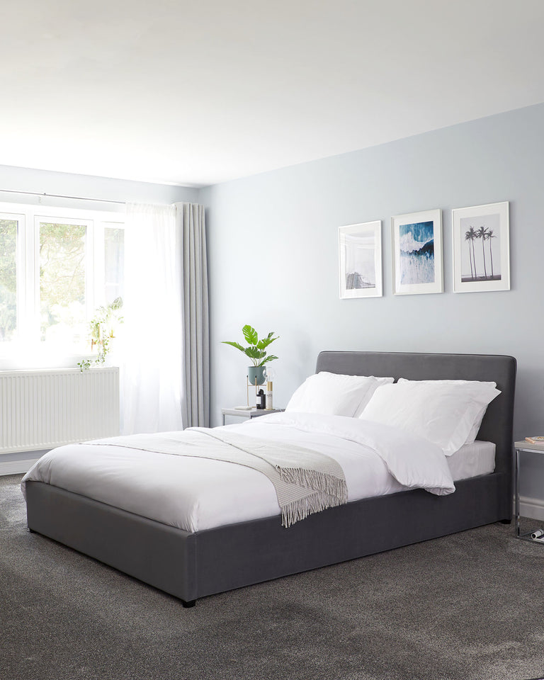 Modern upholstered grey bed frame with headboard and a white bedding set, accompanied by a light grey throw blanket at the foot of the bed.